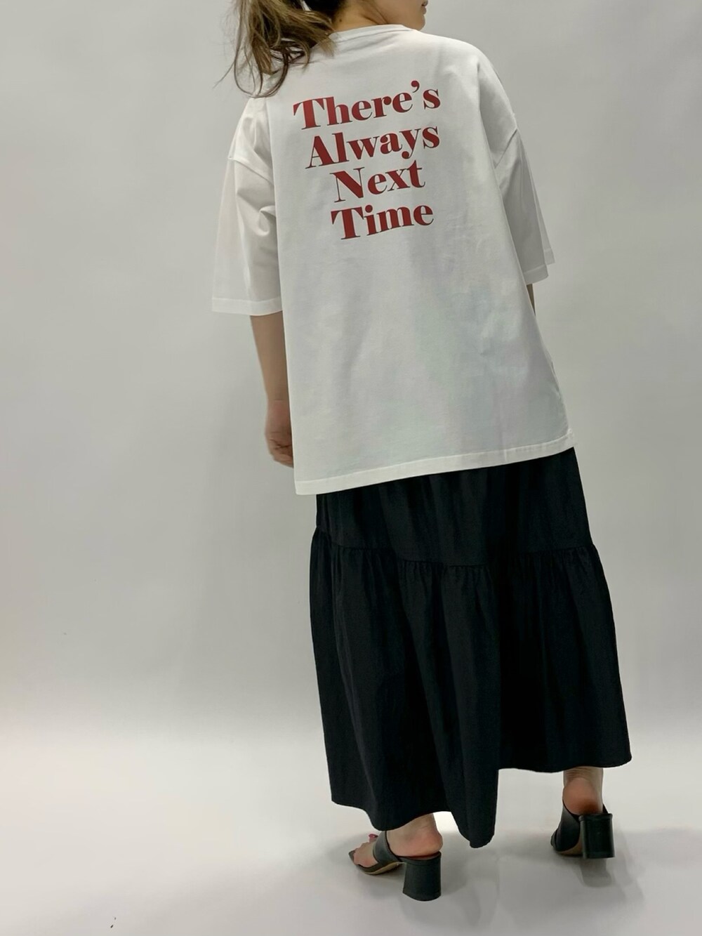 ホワイト系のトップス、ブラック系のスカート、ブラック系のサンダルを着用したレディースの夏コーディネートの3枚目の写真