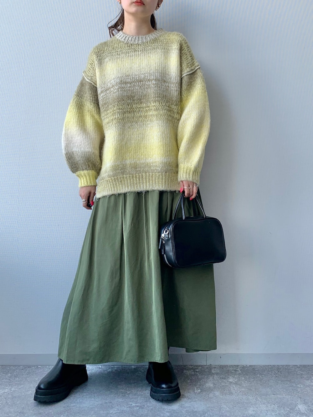 ブラック系のショルダーバッグ、ブラック系のブーツ、グリーン系のスカートを着用したレディースの夏コーディネートの2枚目の写真