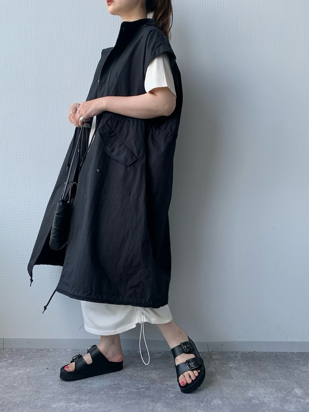 ブラック系のサンダル、ブラック系のジャケット/アウター、ブラック系のバッグを着用したレディースの夏コーディネートの2枚目の写真