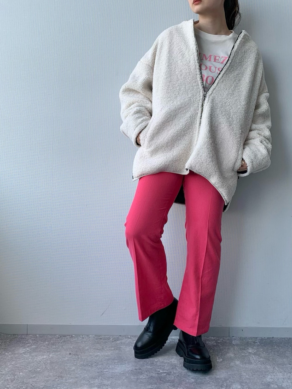 ホワイト系のブルゾン、ピンク系のスラックス、ブラック系のブーツを着用したレディースの夏コーディネートの2枚目の写真