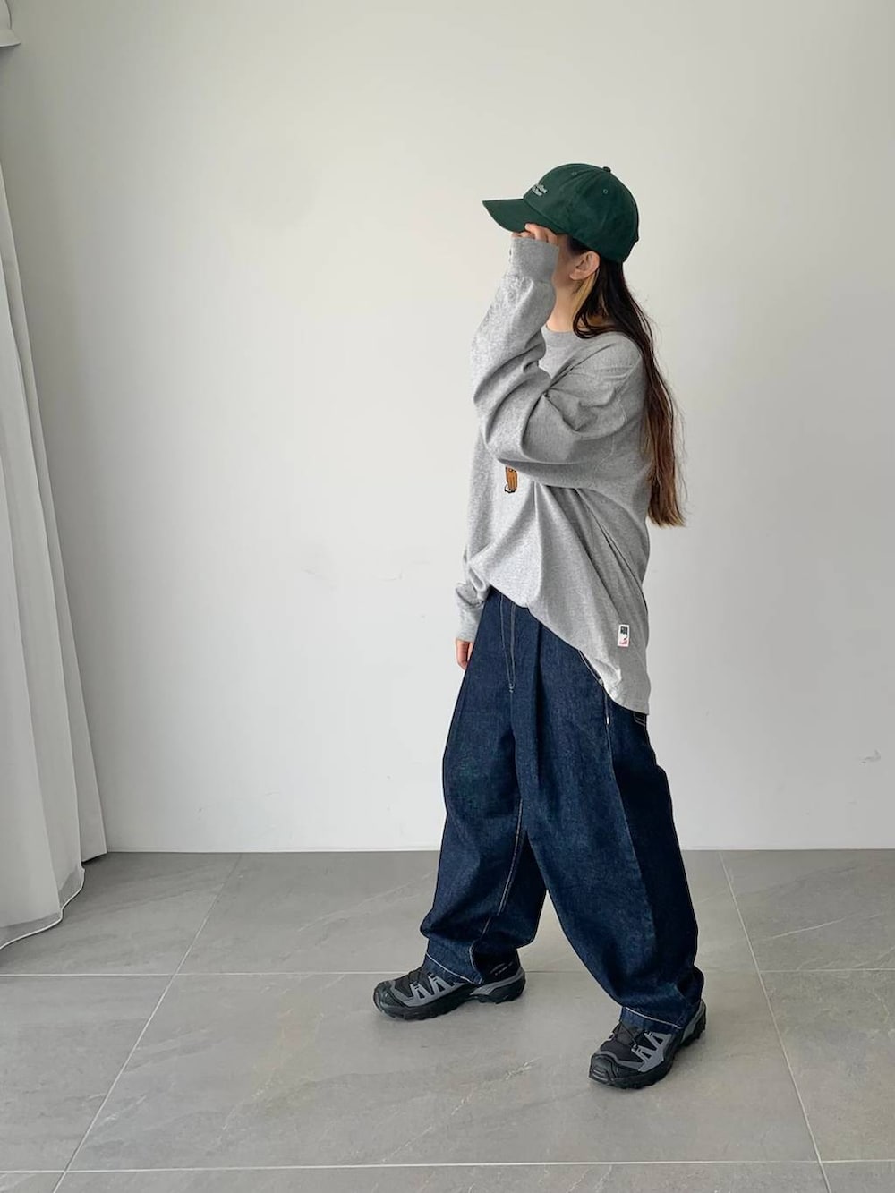 ブルー系のデニムパンツ、グレー系のTシャツ/カットソー、グリーン系のキャップを着用したレディースの夏コーディネートの2枚目の写真