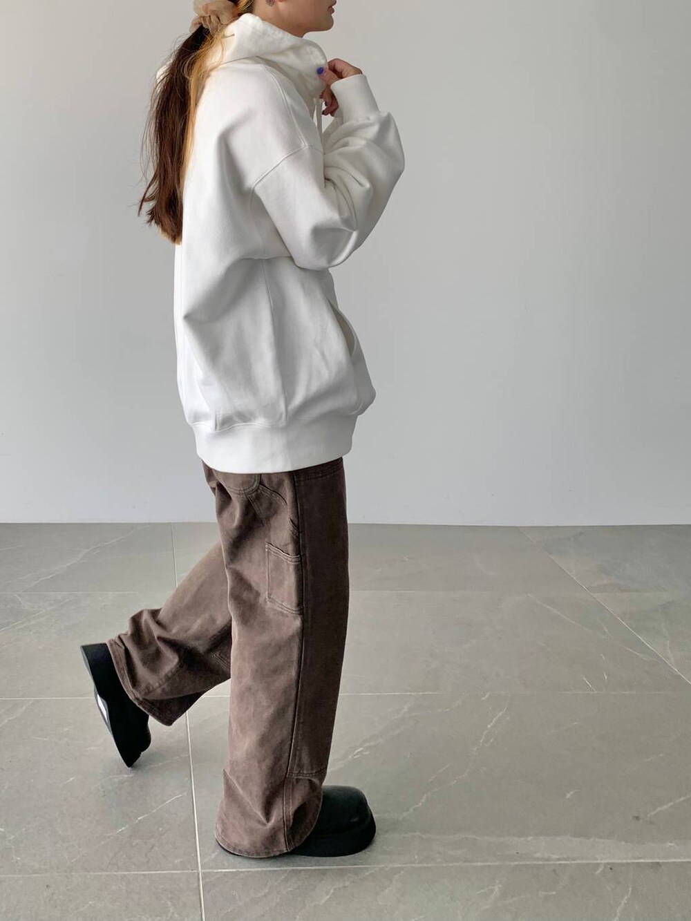 ブラウン系のデニムパンツ、ホワイト系のスウェット、ブラック系のサンダルを着用したレディースの夏コーディネートの3枚目の写真