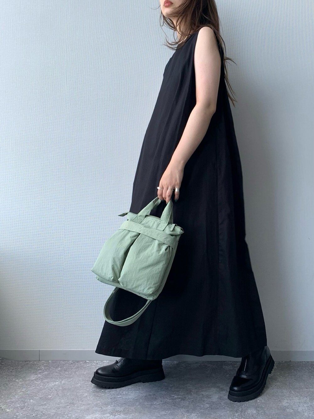 ブラック系のブーツ、ブラック系のワンピース、グリーン系のショルダーバッグを着用したレディースの夏コーディネートの4枚目の写真