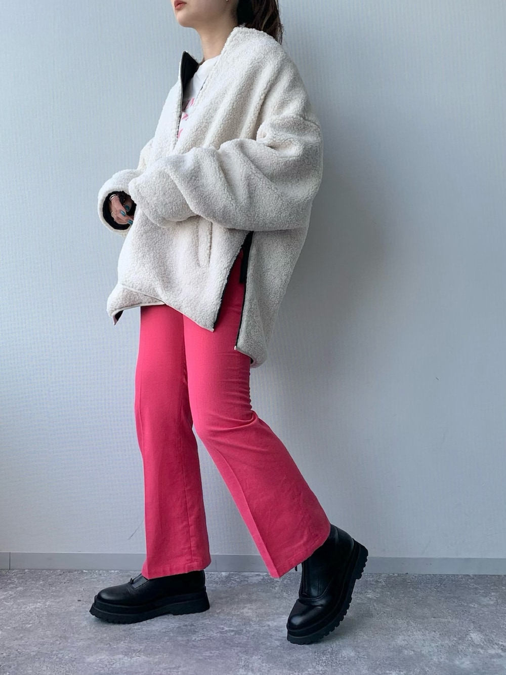 ホワイト系のブルゾン、ピンク系のスラックス、ブラック系のブーツを着用したレディースの夏コーディネートの3枚目の写真