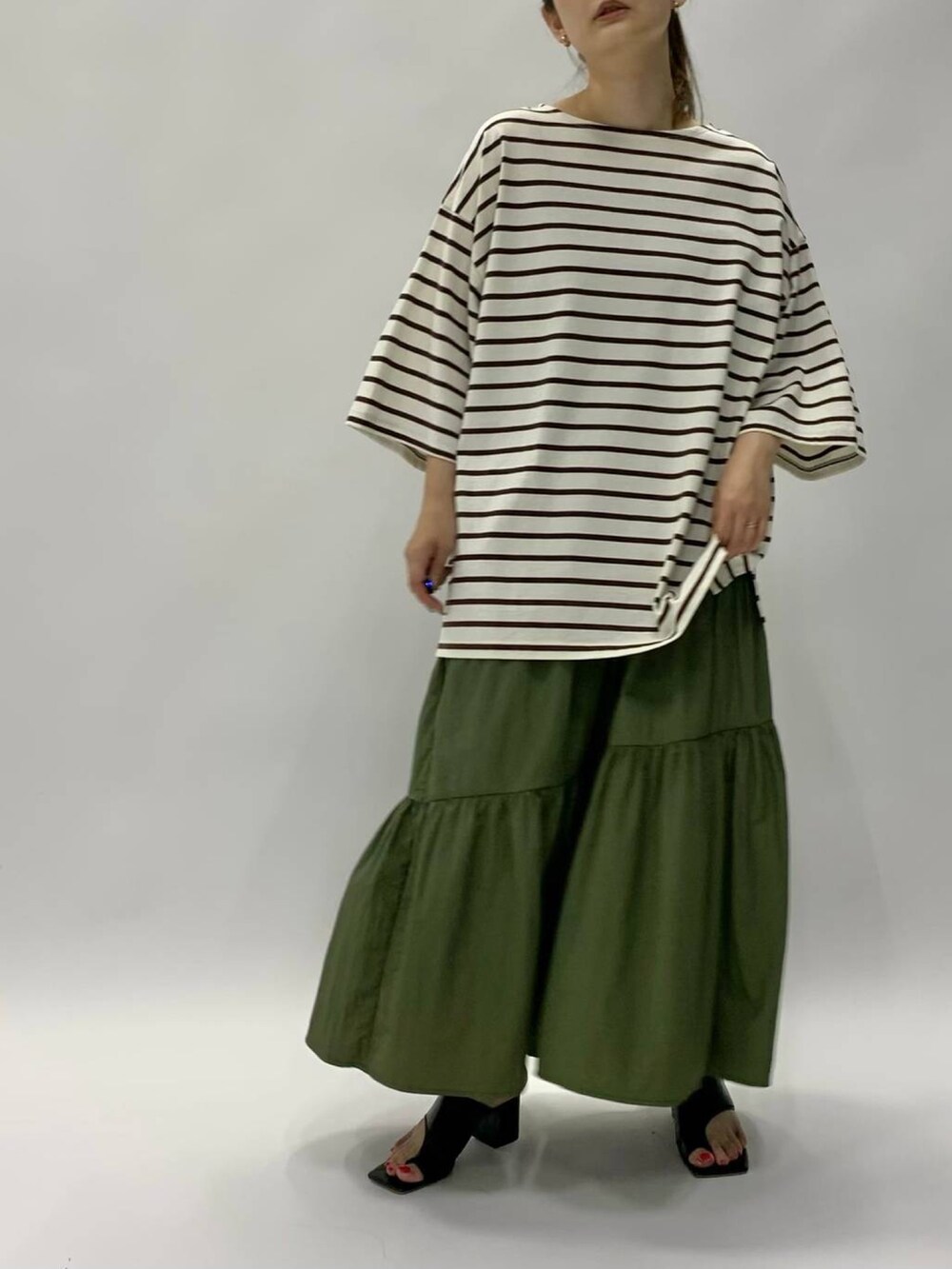 ブラック系のサンダル、グリーン系のスカート、ブラウン系のTシャツ/カットソーを着用したレディースの夏コーディネートの2枚目の写真