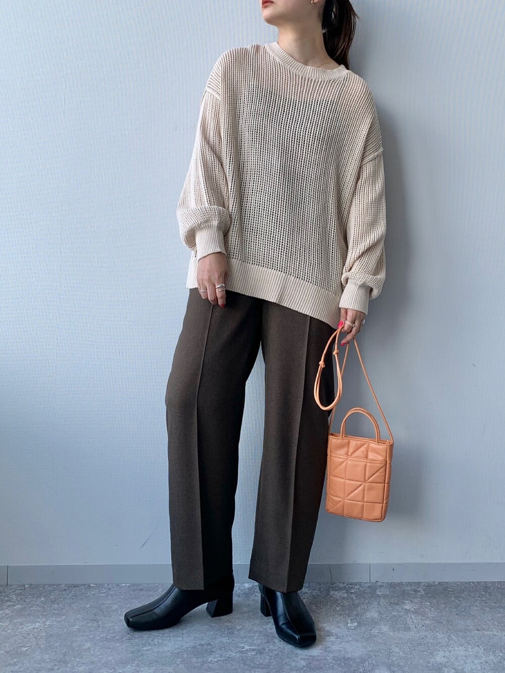 ブラック系のブーツ、オレンジ系のショルダーバッグ、ブラウン系のスラックスを着用したレディースの夏コーディネートの4枚目の写真