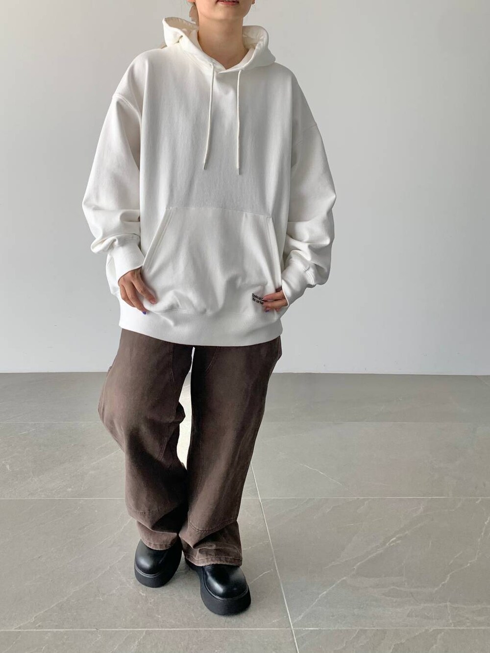 ブラウン系のデニムパンツ、ホワイト系のスウェット、ブラック系のサンダルを着用したレディースの夏コーディネートの5枚目の写真