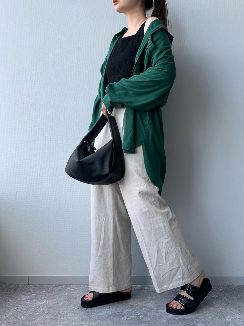 ブラック系のサンダル、ホワイト系のショルダーバッグ、グリーン系のトップスを着用したレディースの夏コーディネートの2枚目の写真
