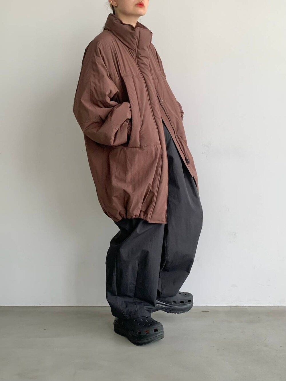 ブラック系のスラックス、ブラウン系のブルゾンを着用したレディースの夏コーディネートの2枚目の写真