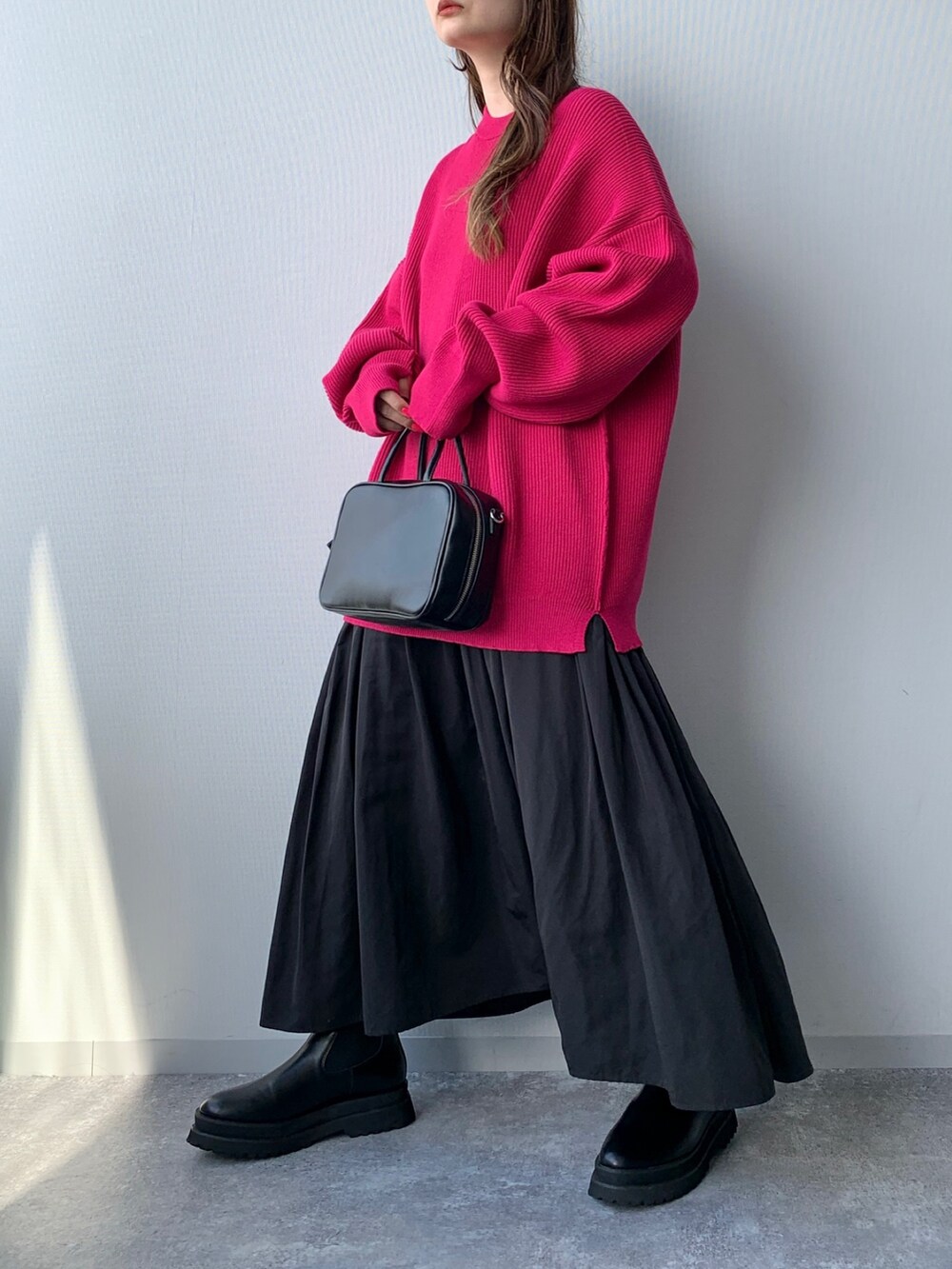 ブラック系のブーツ、ブラック系のスカート、ピンク系のニット/セーターを着用したレディースの夏コーディネートの2枚目の写真