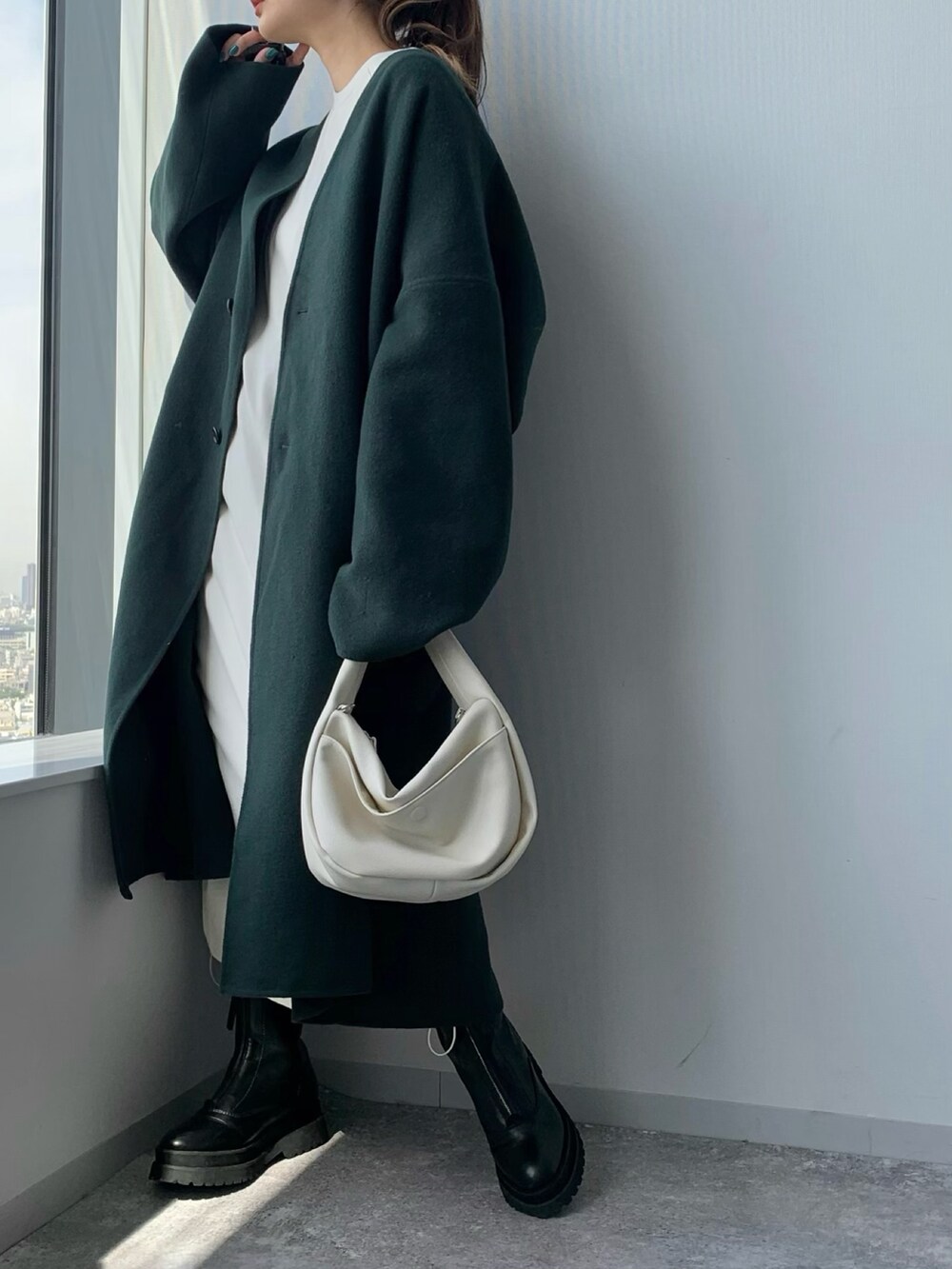 ホワイト系のショルダーバッグ、ブラック系のブーツ、グリーン系のノーカラーコートを着用したレディースの夏コーディネートの5枚目の写真