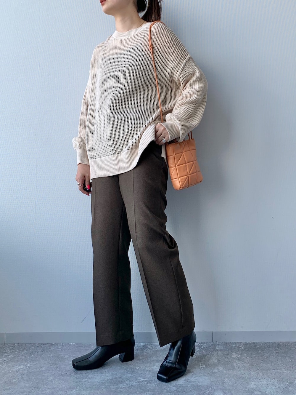 ブラック系のブーツ、オレンジ系のショルダーバッグ、ブラウン系のスラックスを着用したレディースの夏コーディネートの3枚目の写真