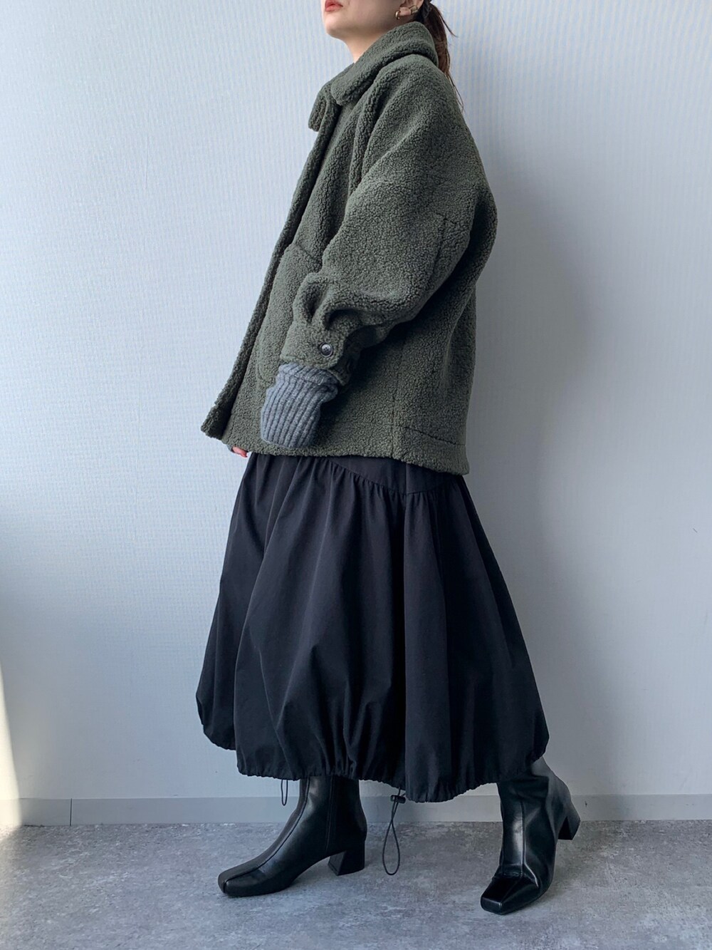 ブラック系のブーツ、グリーン系のブルゾン、ブラック系のワンピースを着用したレディースの夏コーディネートの2枚目の写真