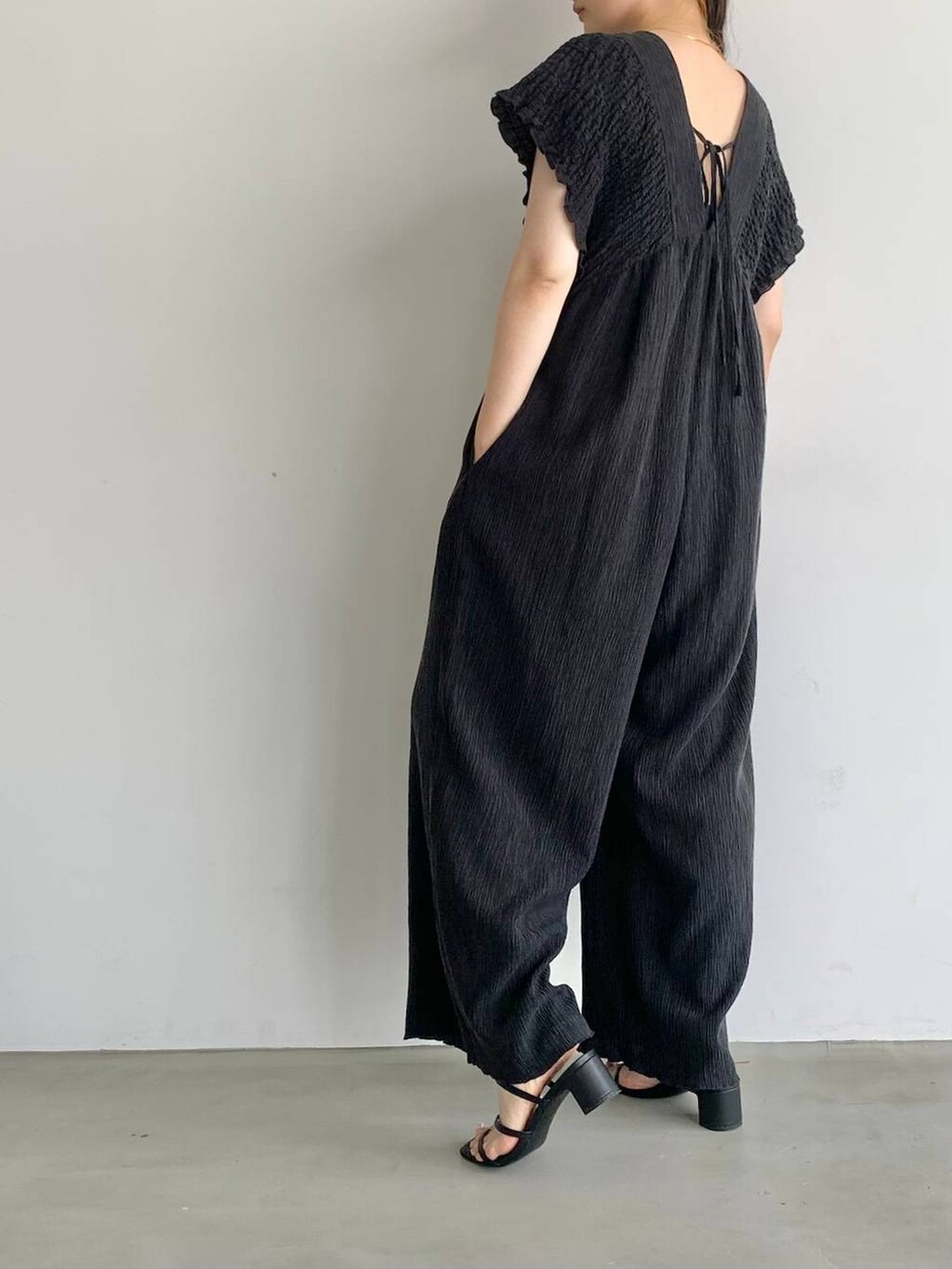 ブラック系のサロペット/オーバーオール、ブラック系のサンダル、レッド系のキャップを着用したレディースの夏コーディネートの3枚目の写真