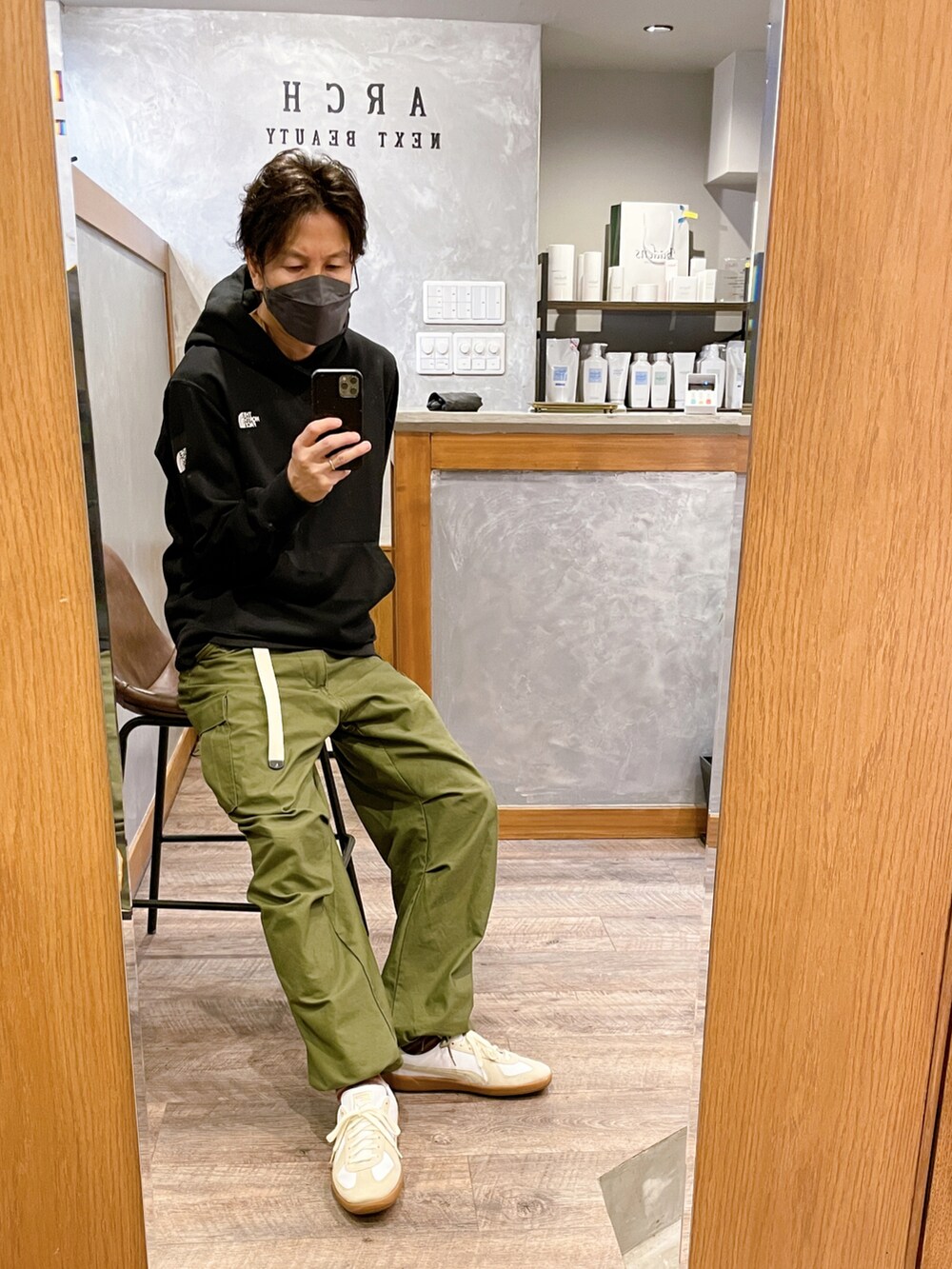 ホワイト系のスニーカー、グリーン系のカーゴパンツ、ブラック系のパーカーを着用したメンズの秋コーディネートの3枚目の写真