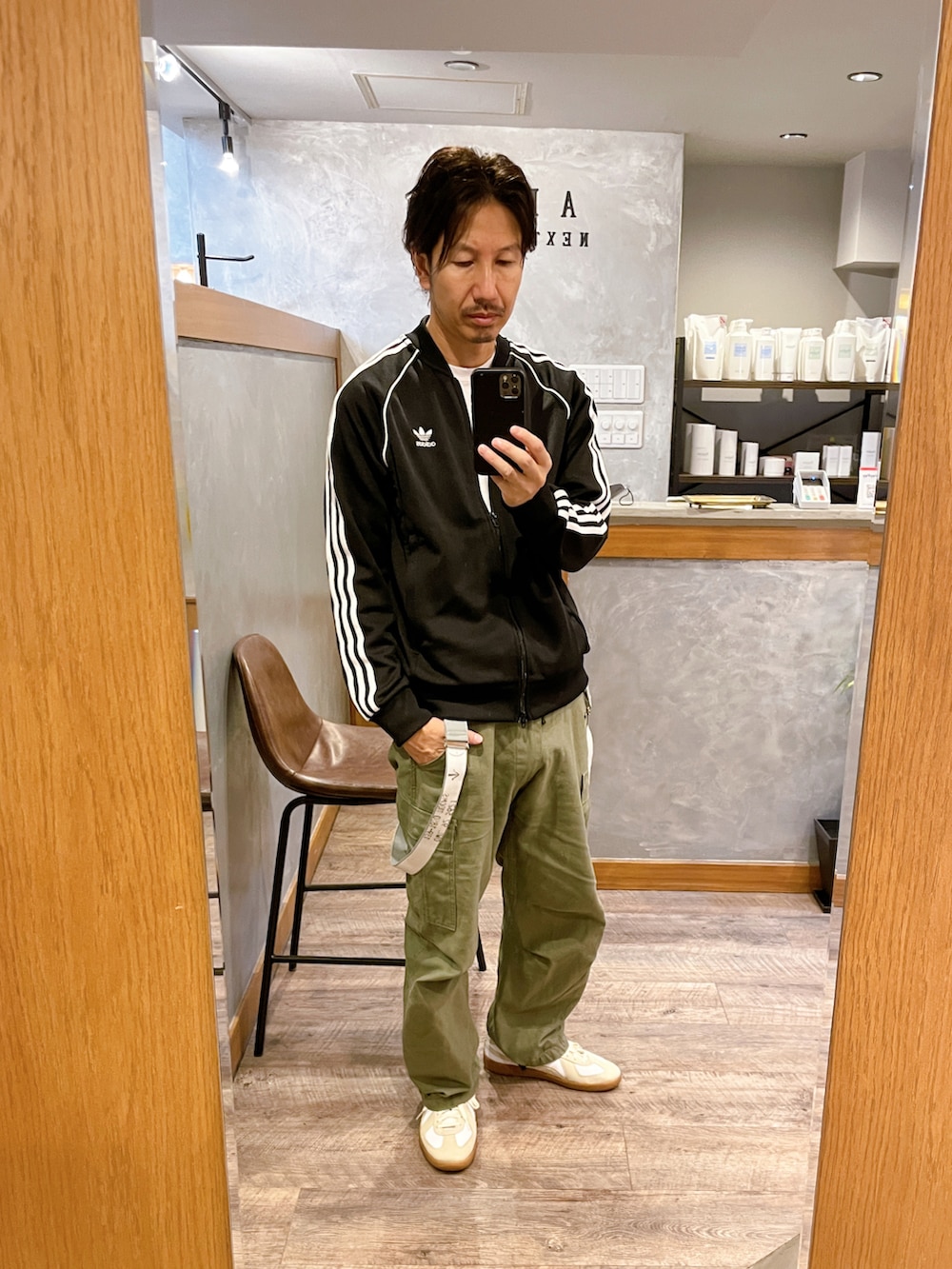ホワイト系のスニーカー、グリーン系のカーゴパンツ、ブラック系のマウンテンパーカーを着用したメンズの秋コーディネートの2枚目の写真