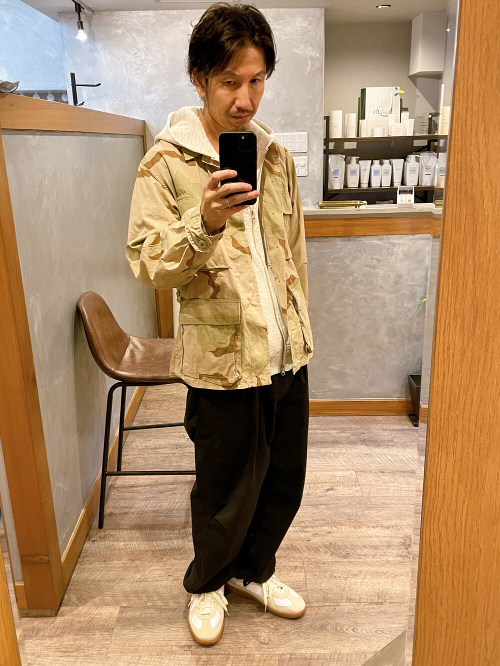 ホワイト系のスニーカー、ブルー系のパンツ、その他のミリタリージャケットを着用したメンズの秋コーディネートの2枚目の写真