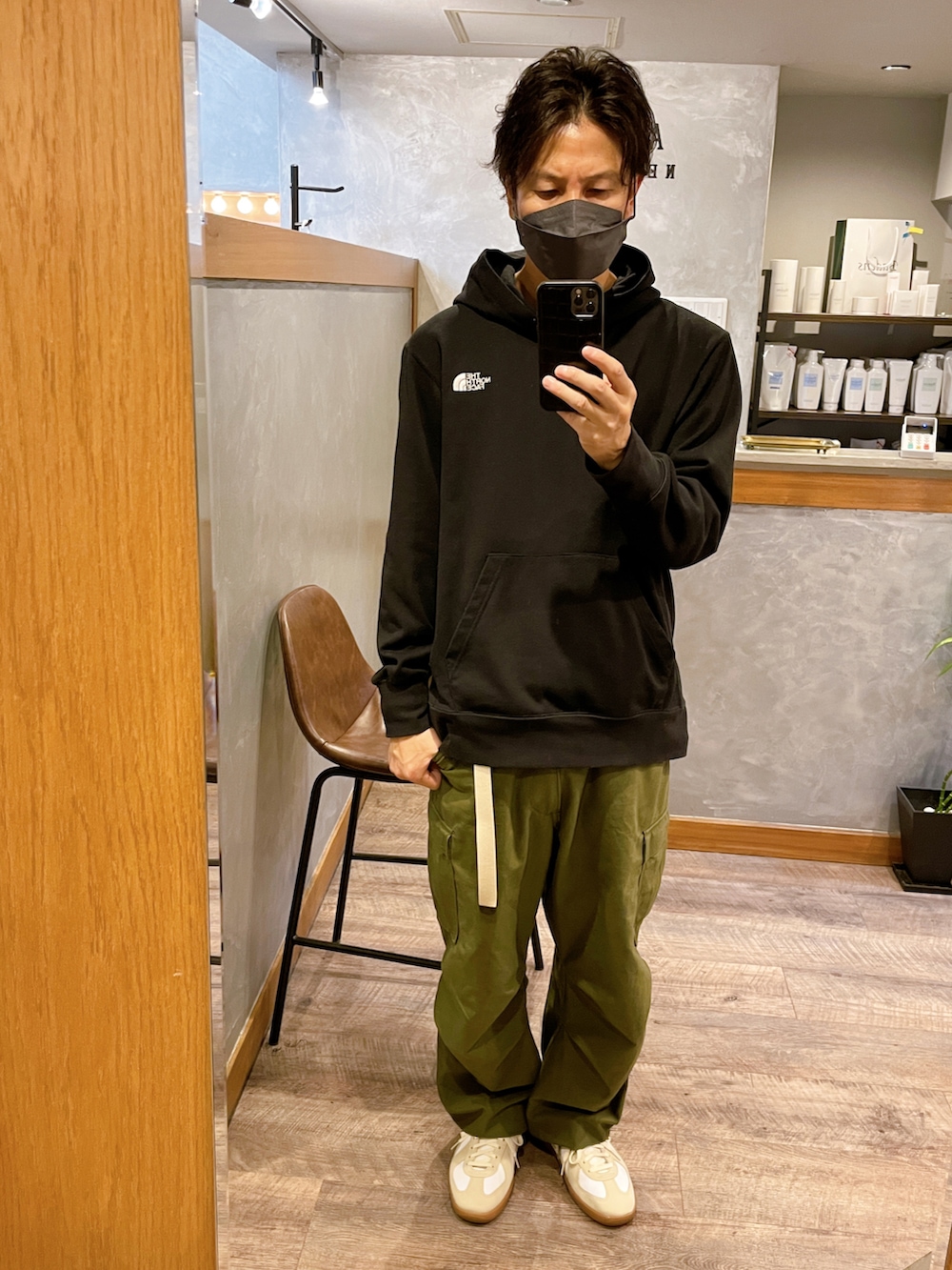 ホワイト系のスニーカー、グリーン系のカーゴパンツ、ブラック系のパーカーを着用したメンズの秋コーディネートの2枚目の写真