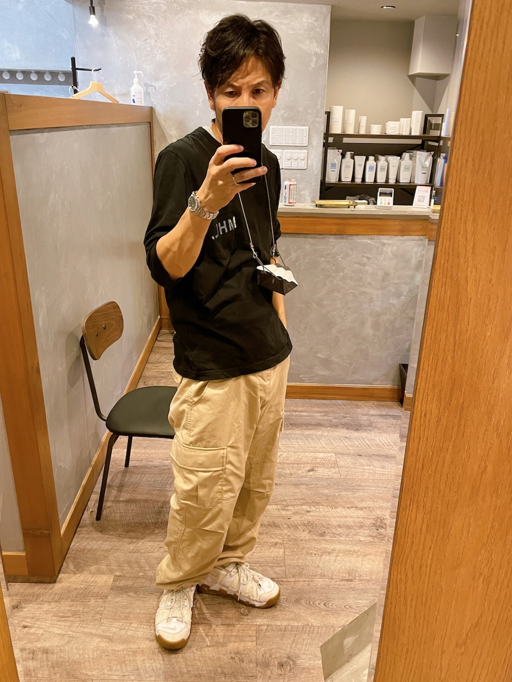 ホワイト系のスニーカー、ベージュ系のカーゴパンツ、ブラック系のTシャツ/カットソーを着用したメンズの秋コーディネートの2枚目の写真