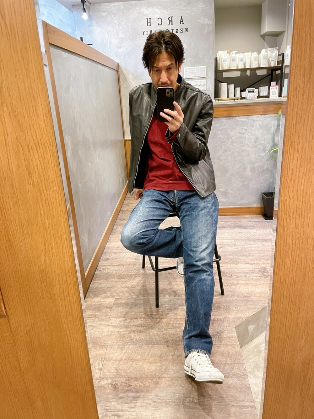 ブルー系のデニムパンツ、ホワイト系のスニーカー、ブラック系のライダースジャケットを着用したメンズの秋コーディネートの2枚目の写真