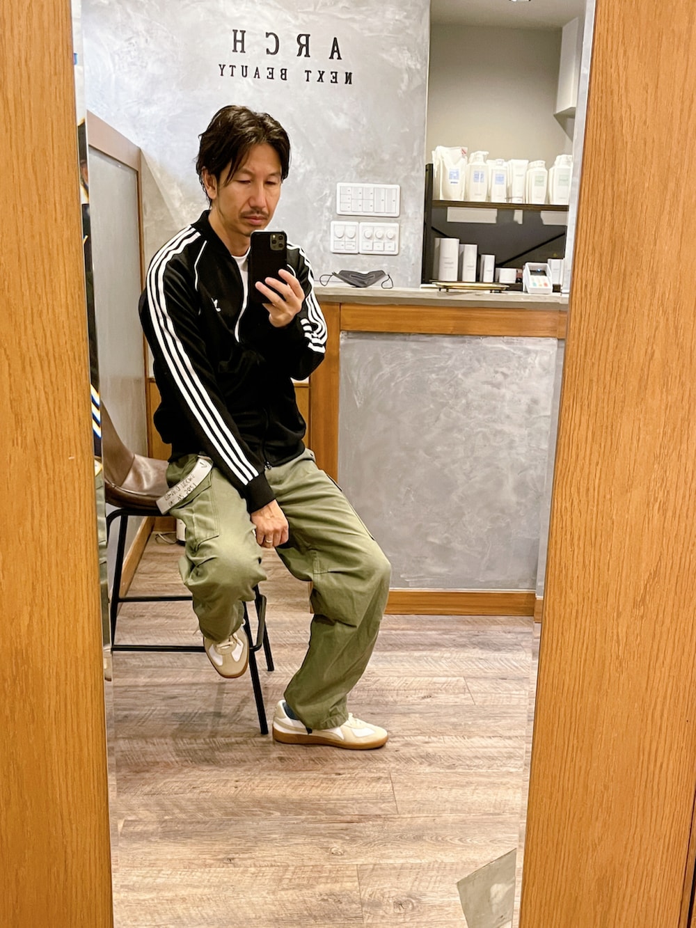 ホワイト系のスニーカー、グリーン系のカーゴパンツ、ブラック系のマウンテンパーカーを着用したメンズの秋コーディネートの3枚目の写真