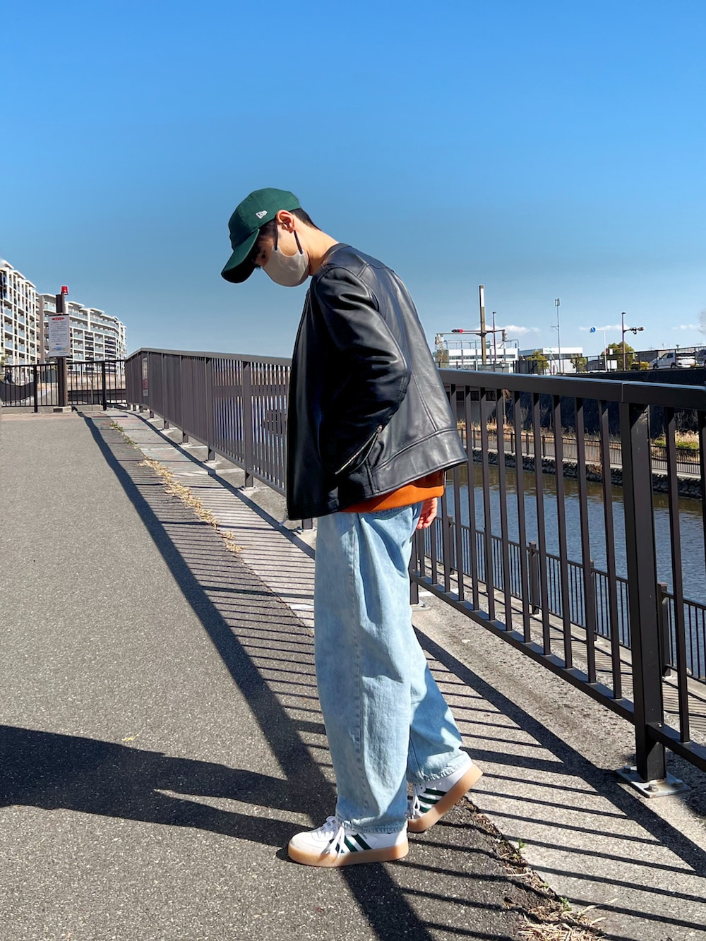 ブラック系のライダースジャケット、ブルー系のデニムパンツ、ホワイト系のスニーカーを着用したメンズの春コーディネートの2枚目の写真