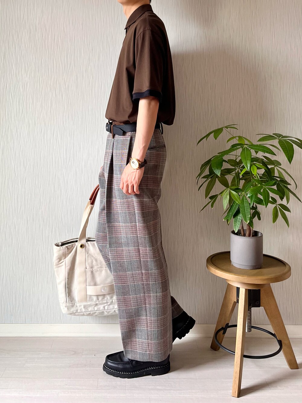 ブラウン系のポロシャツ、ホワイト系のトートバッグ、グレー系のスラックスを着用したメンズの秋コーディネートの2枚目の写真
