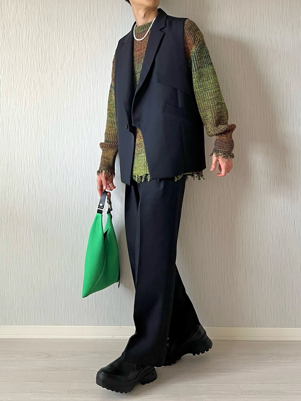ブラック系のテーラードジャケット、グリーン系のトートバッグ、ブラック系のスラックスを着用したメンズの秋コーディネートの2枚目の写真