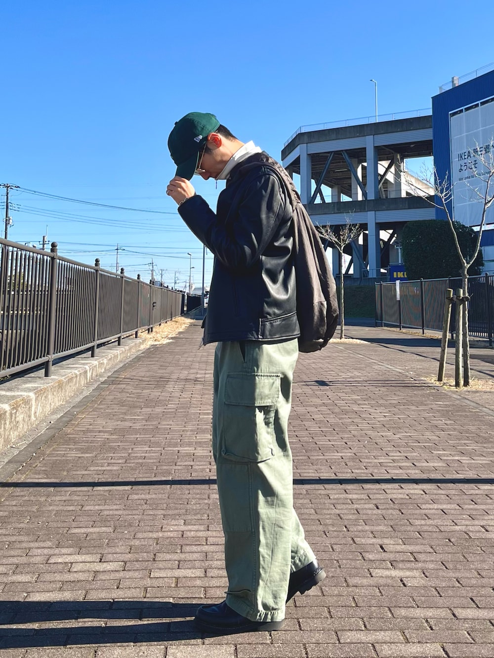 グリーン系のカーゴパンツ、グレー系のショルダーバッグ、ブラック系のライダースジャケットを着用したメンズの冬コーディネートの2枚目の写真