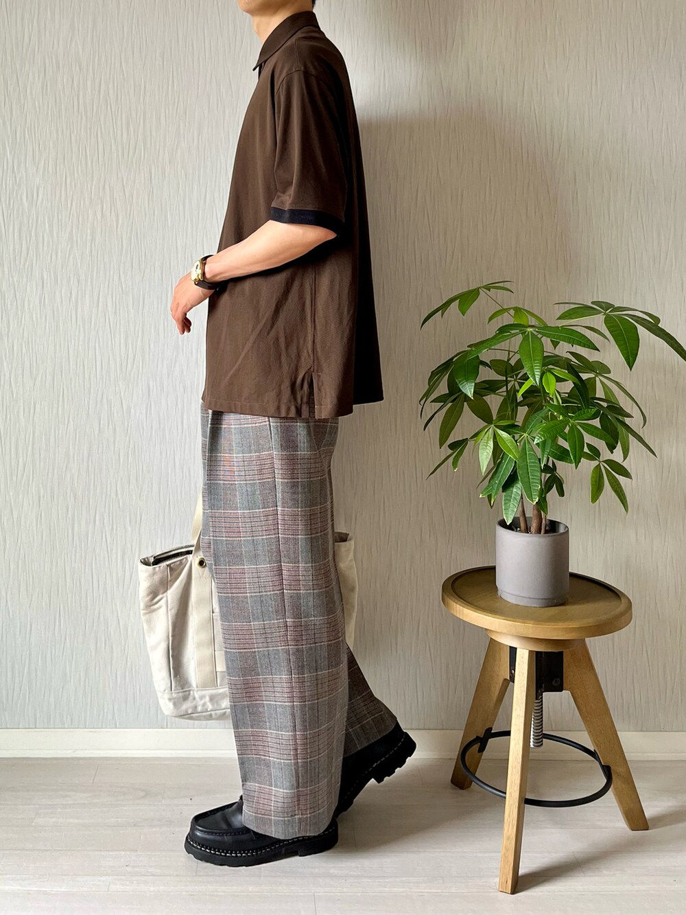 ブラウン系のポロシャツ、ホワイト系のトートバッグ、グレー系のスラックスを着用したメンズの秋コーディネートの4枚目の写真