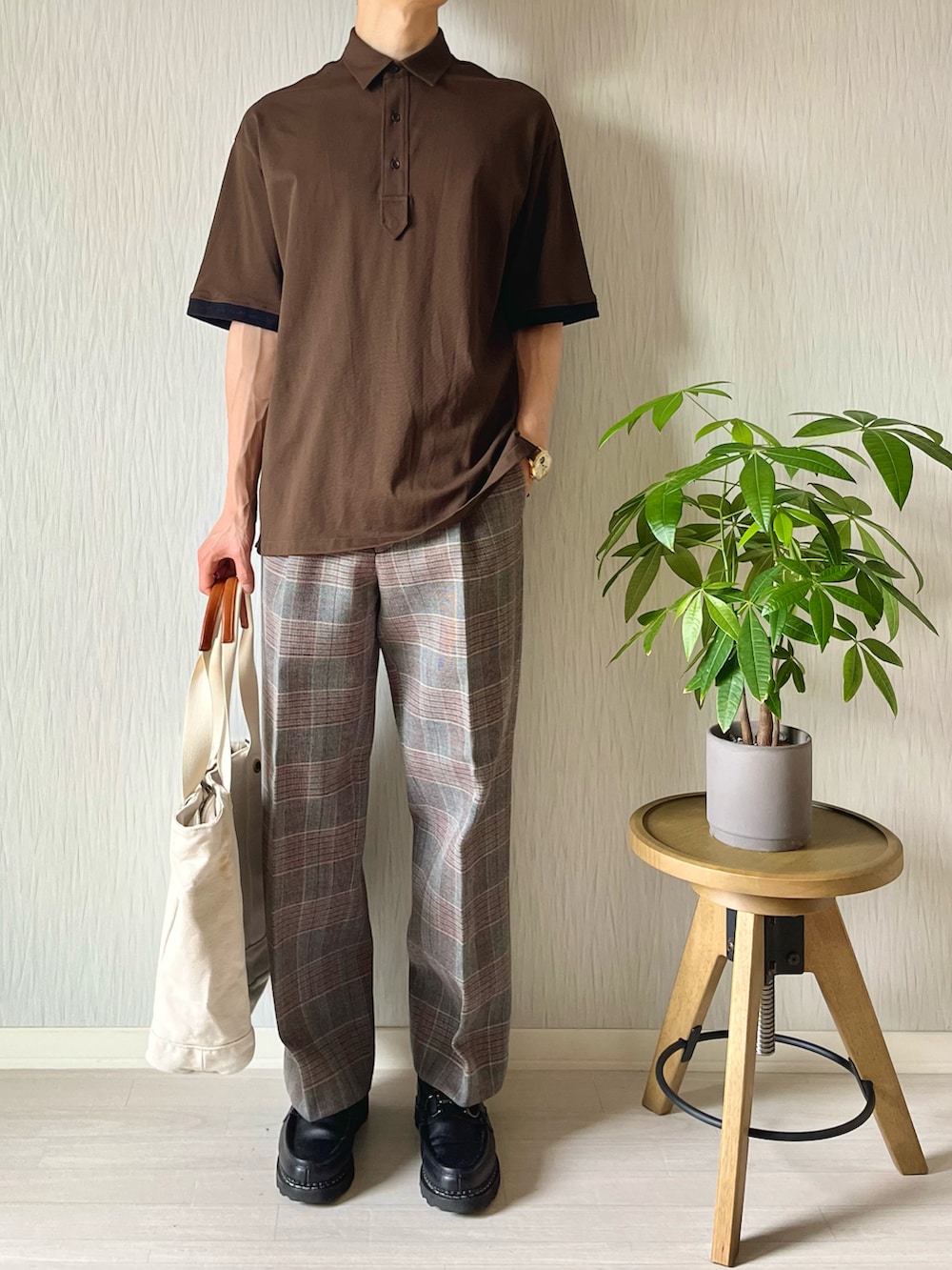 ブラウン系のポロシャツ、ホワイト系のトートバッグ、グレー系のスラックスを着用したメンズの秋コーディネートの3枚目の写真