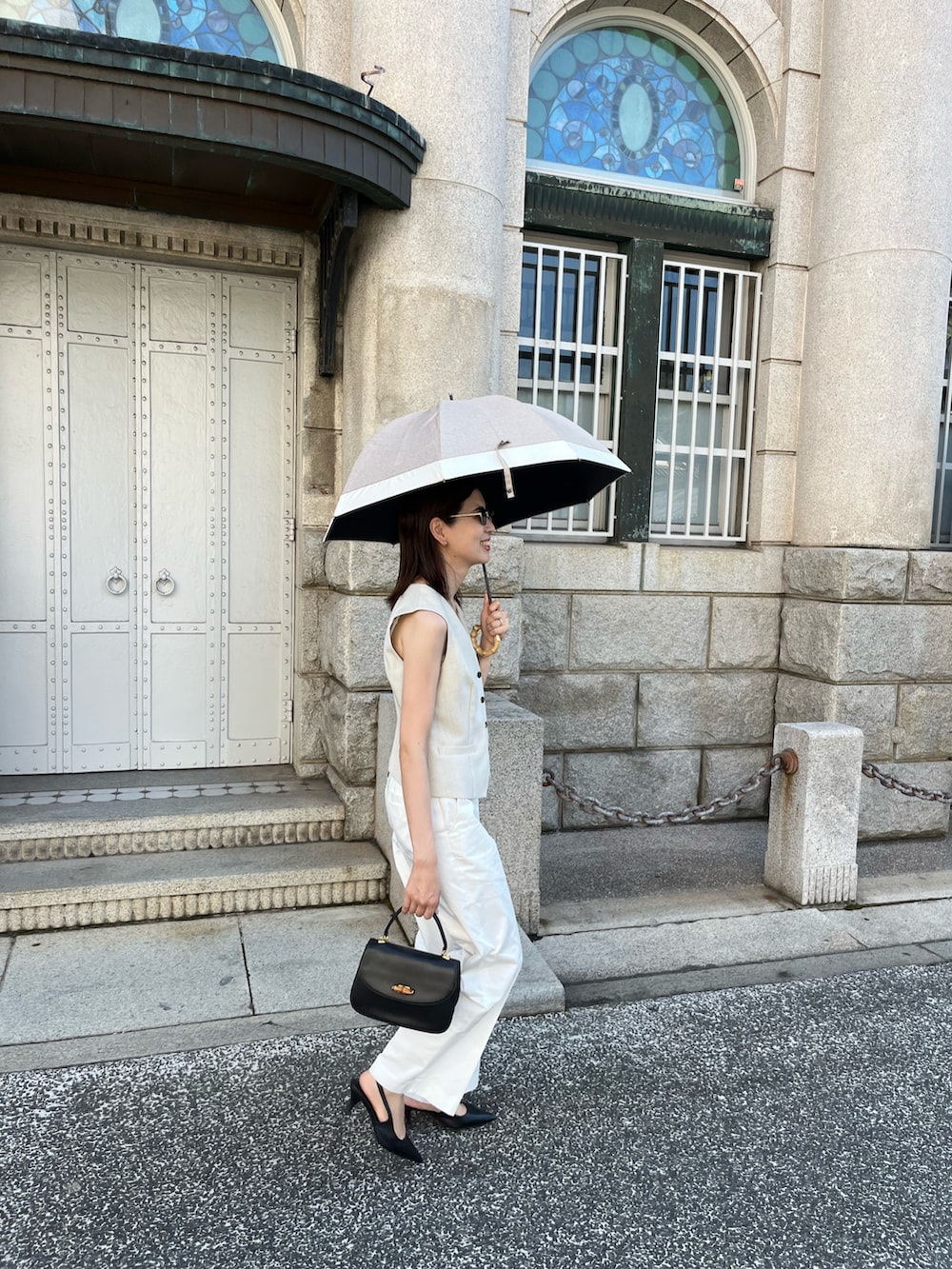 ブラック系のハンドバッグ、ホワイト系のチノパンツ、ベージュ系のベストを着用したレディースの秋コーディネートの2枚目の写真