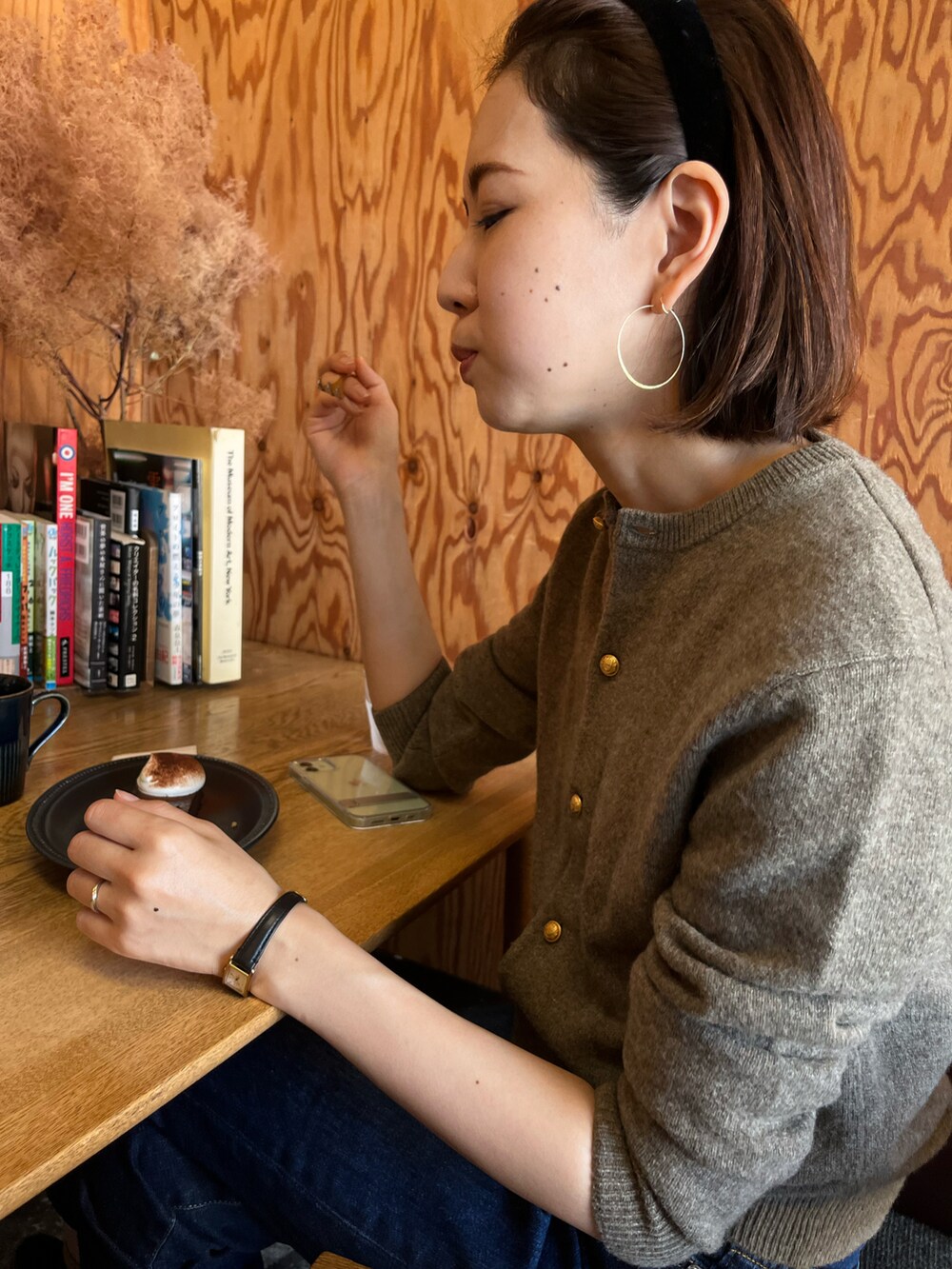 ブラウン系のショルダーバッグ、ブルー系のデニムパンツ、ブラック系のブーツを着用したレディースの秋コーディネートの2枚目の写真