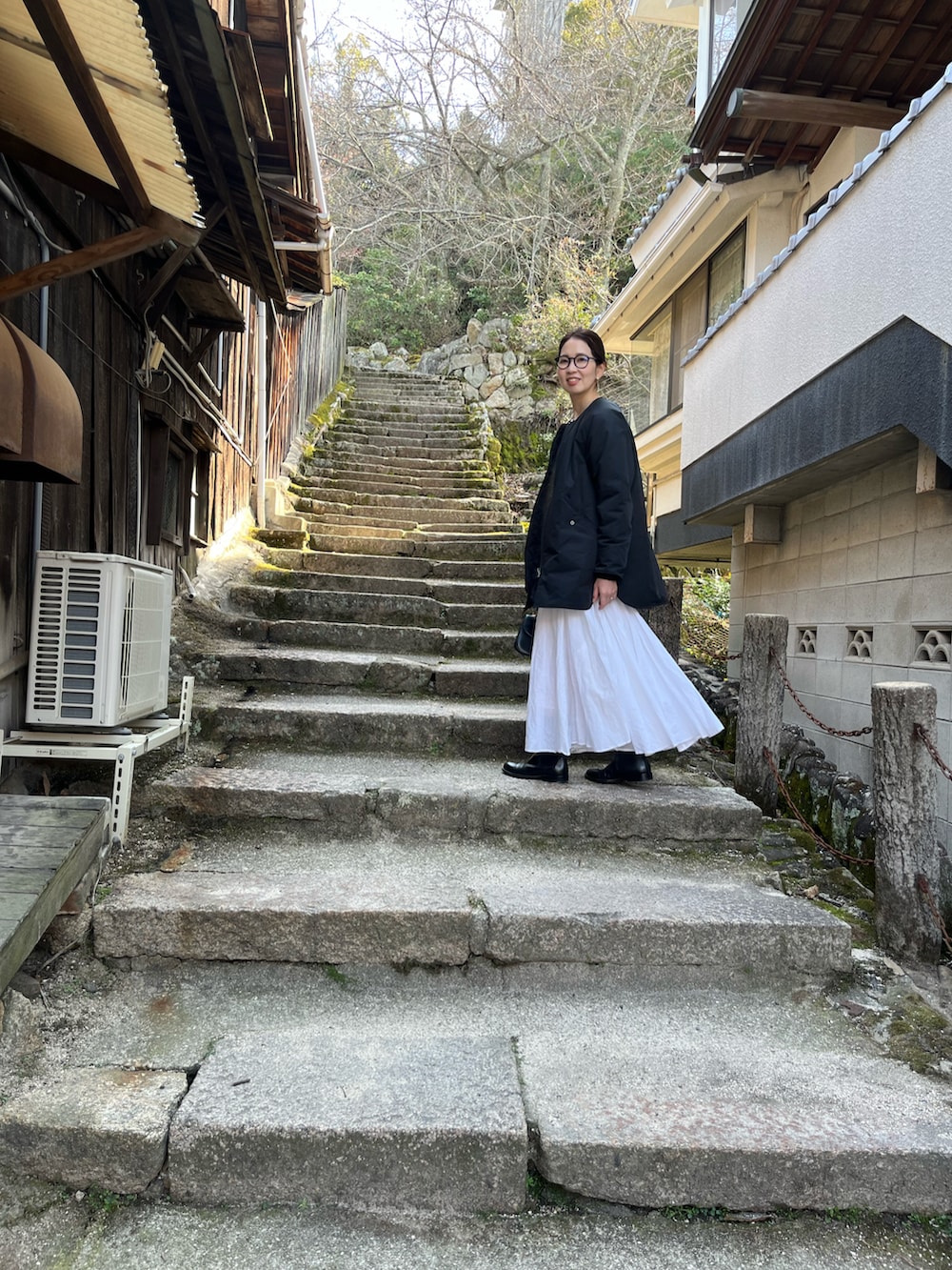 ブラック系のその他アウター、ホワイト系のスカート、ブラック系のブーツを着用したレディースの春コーディネートの2枚目の写真