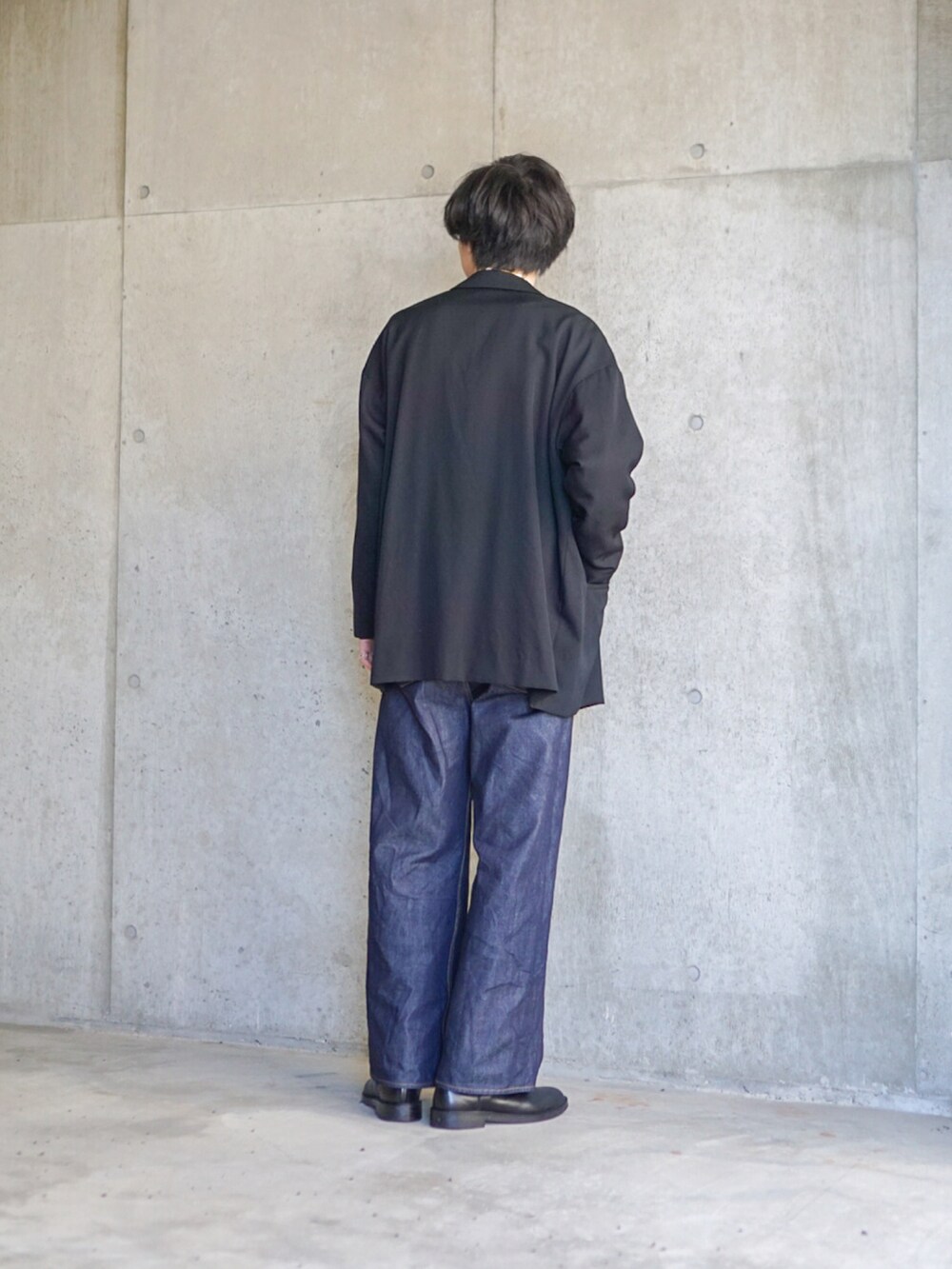 ブラック系のテーラードジャケット、ホワイト系のTシャツ/カットソー、ブルー系のデニムパンツを着用したメンズの春コーディネートの4枚目の写真