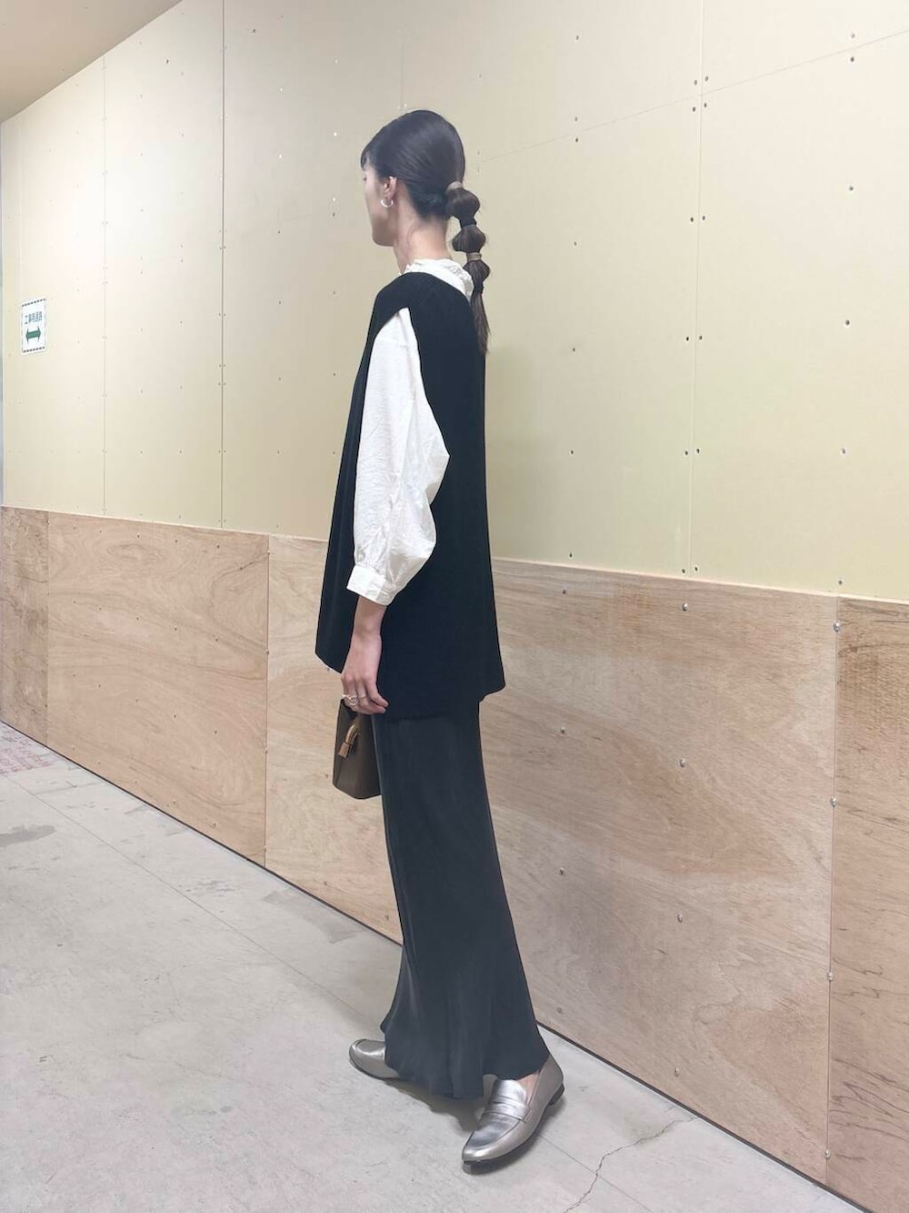 ブラウン系のハンドバッグ、ホワイト系のシャツ/ブラウス、ブラック系のベストを着用したレディースの秋コーディネートの2枚目の写真