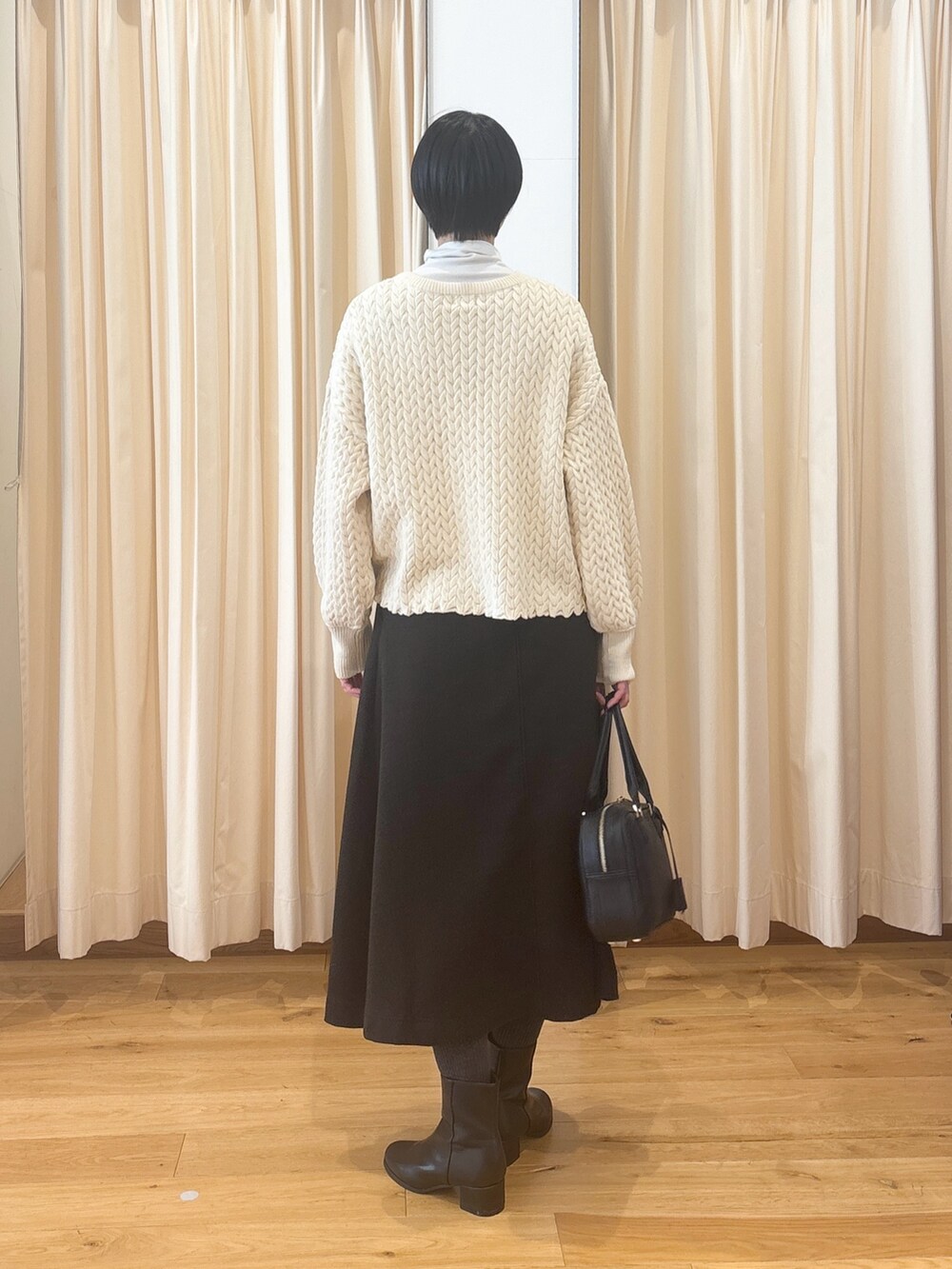 ブラック系のブーツ、ブラウン系のスカート、ブラック系のボストンバッグを着用したレディースの冬コーディネートの7枚目の写真