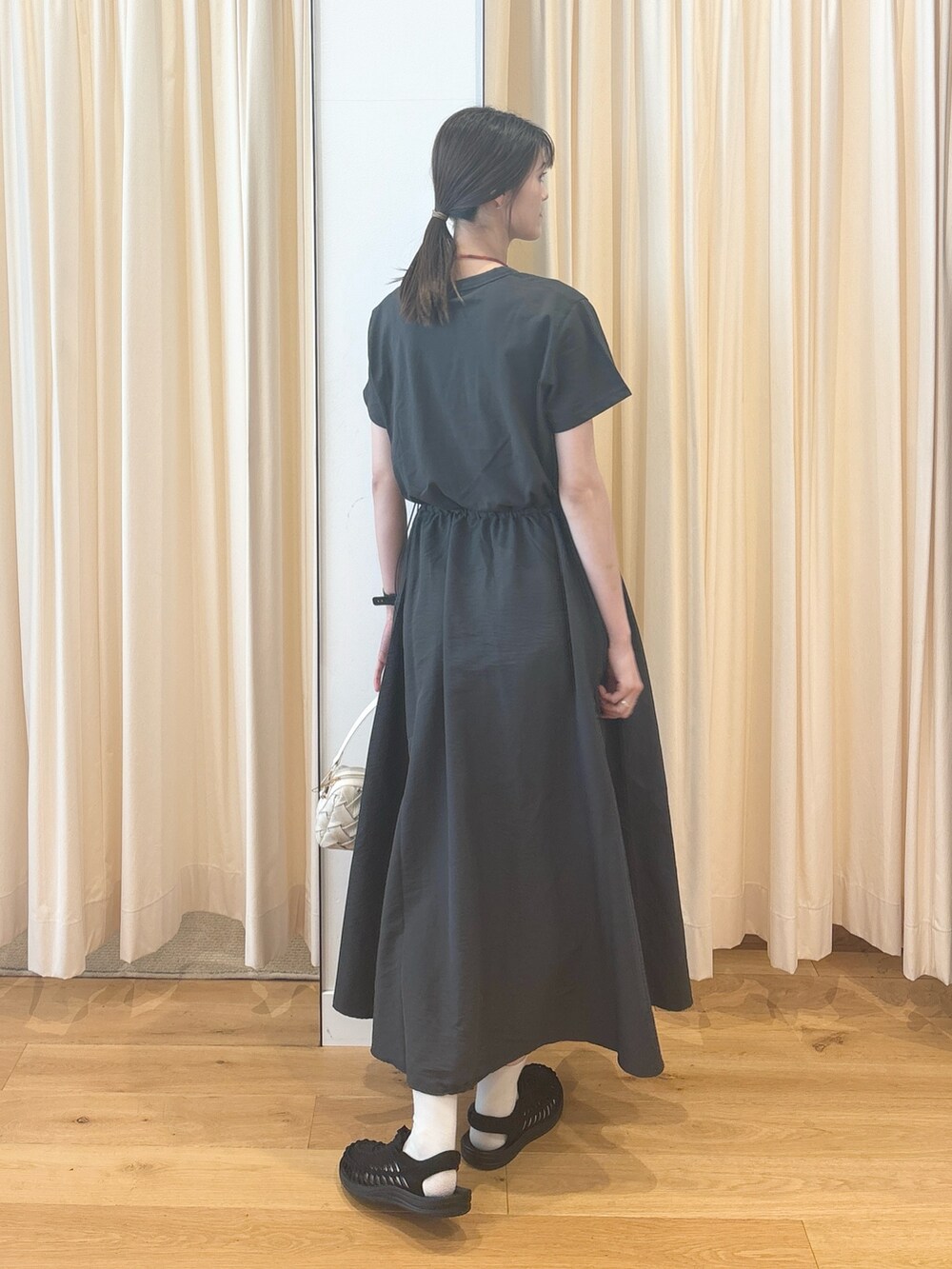 ホワイト系のショルダーバッグ、ブルー系のカーディガン/ボレロ、グレー系のワンピースを着用したレディースの夏コーディネートの3枚目の写真