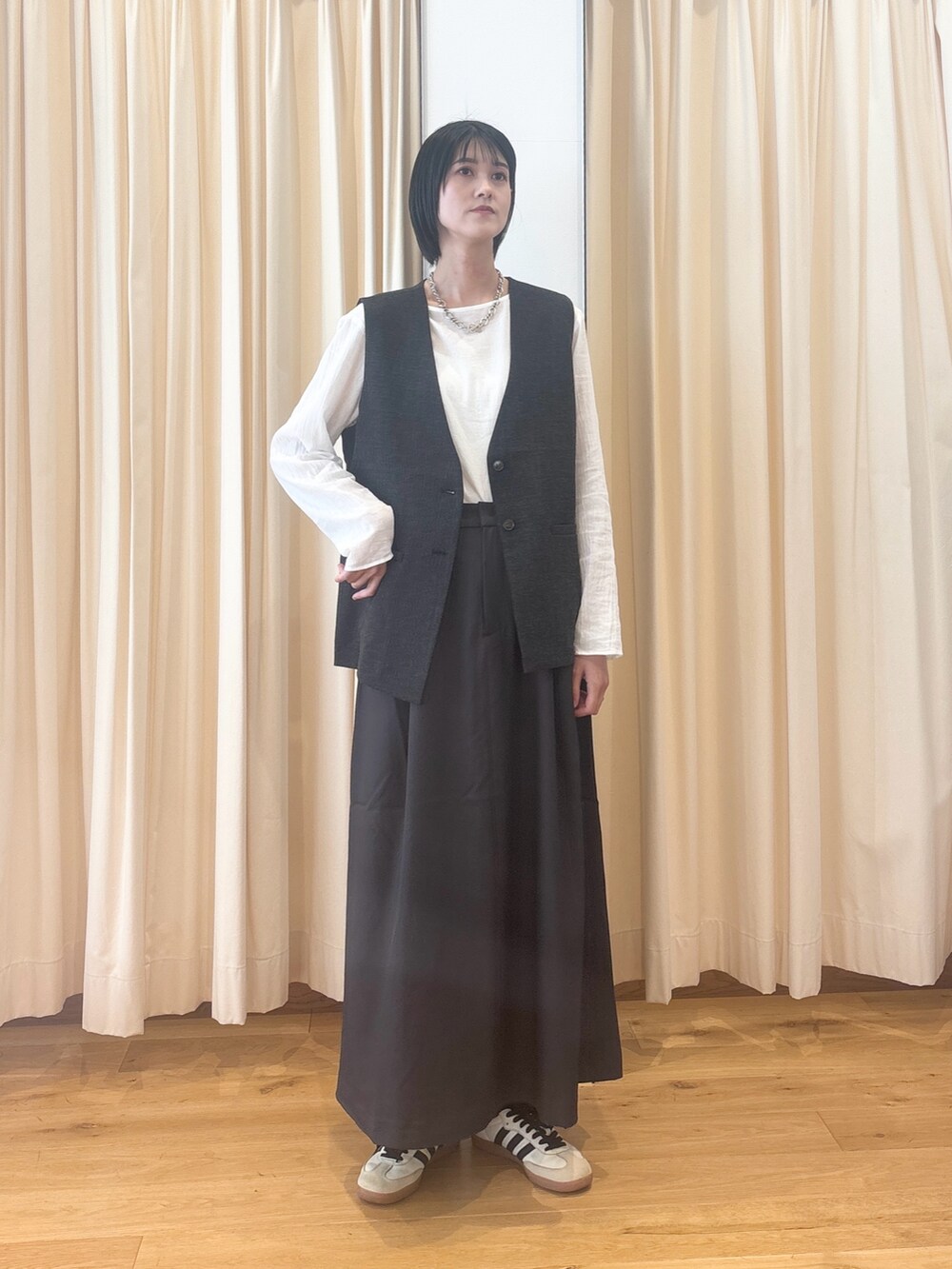 ブラック系のその他アウター、ホワイト系のシャツ/ブラウス、グレー系のスカートを着用したレディースの秋コーディネートの2枚目の写真
