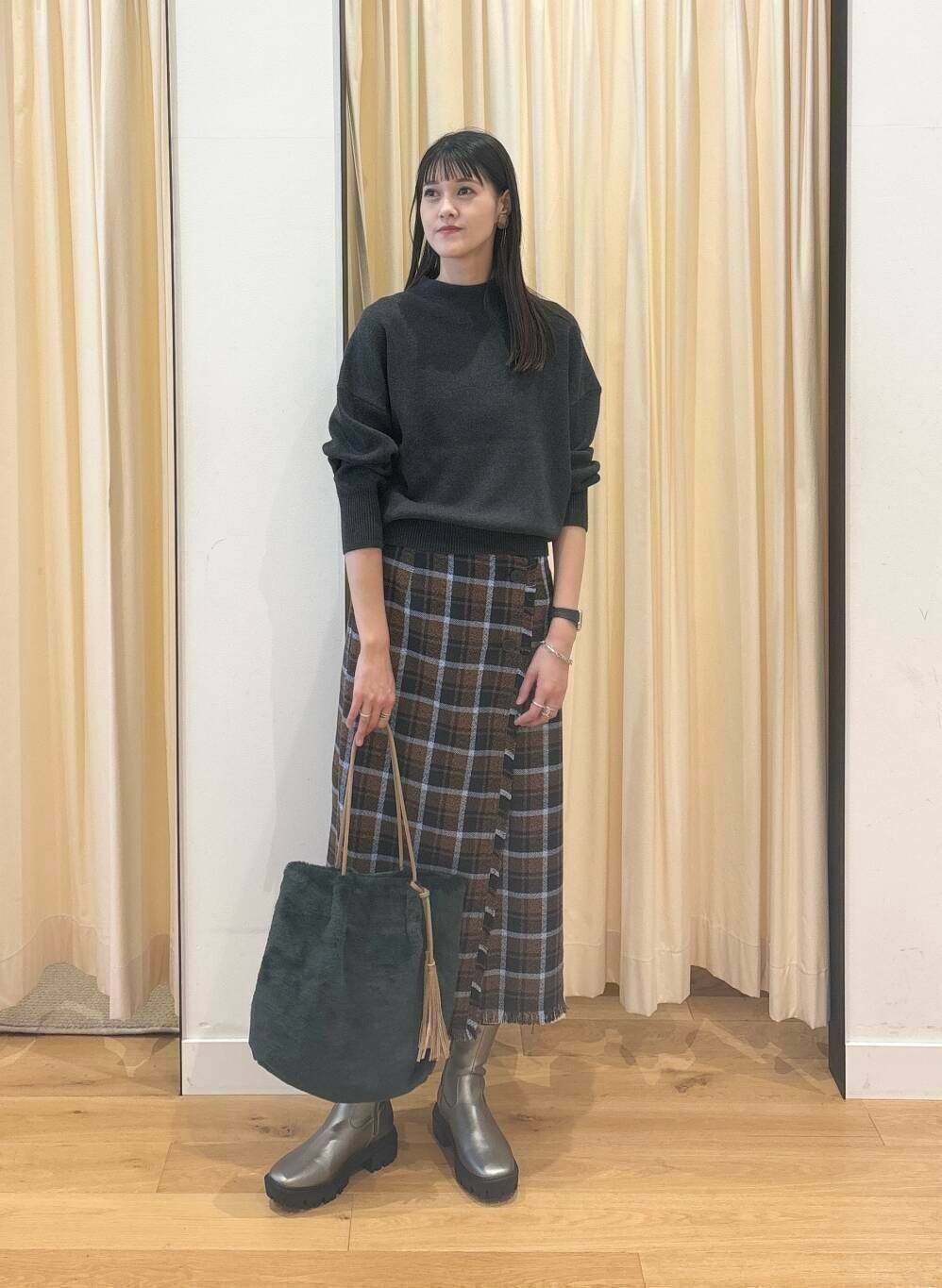 グレー系のニット/セーター、シルバー系のブーツ、ブラウン系のスカートを着用したレディースの秋コーディネートの2枚目の写真