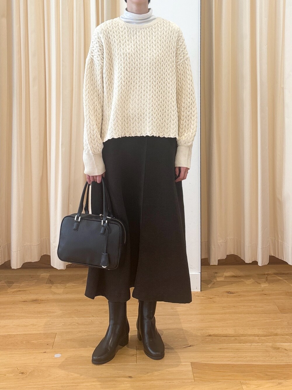 ブラック系のブーツ、ブラウン系のスカート、ブラック系のボストンバッグを着用したレディースの冬コーディネートの8枚目の写真