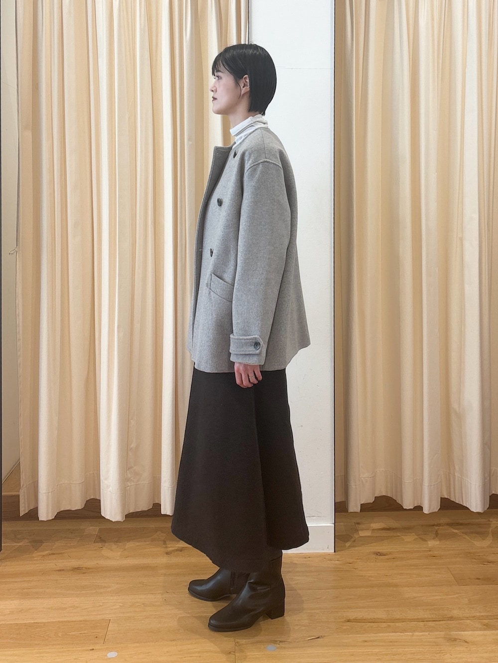 ブラック系のブーツ、ブラウン系のスカート、ブラック系のボストンバッグを着用したレディースの冬コーディネートの2枚目の写真