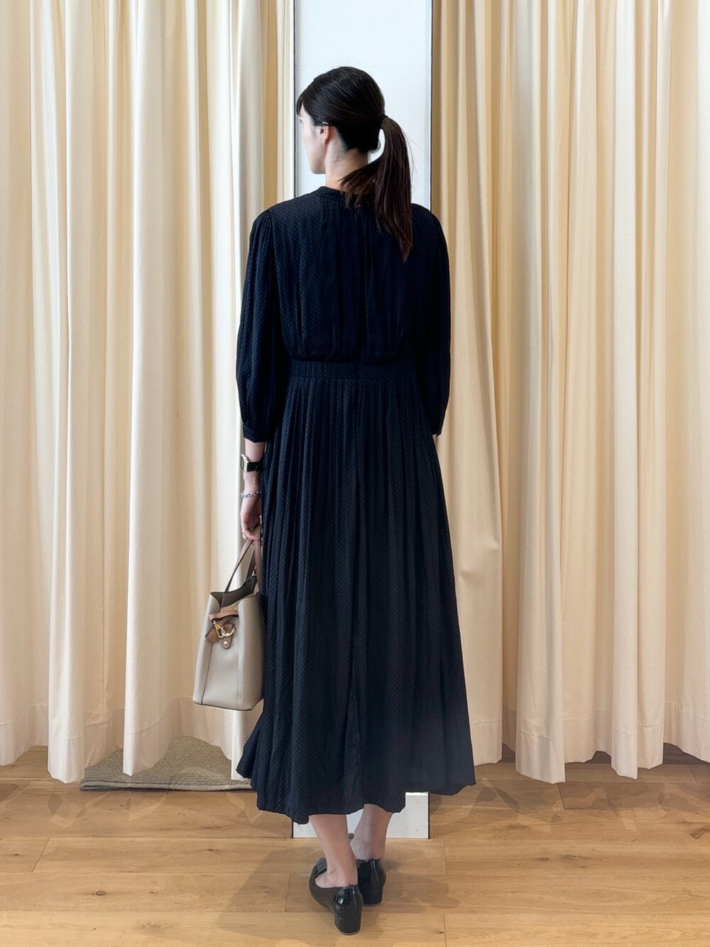 ブルー系のワンピース、ブラック系のパンプス、ベージュ系のトートバッグを着用したレディースの秋コーディネートの2枚目の写真