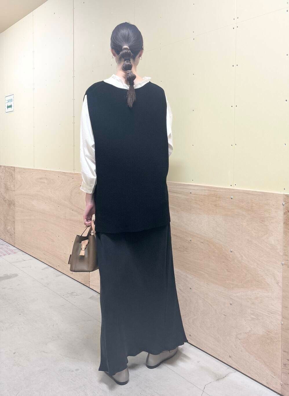 ブラウン系のハンドバッグ、ホワイト系のシャツ/ブラウス、ブラック系のベストを着用したレディースの秋コーディネートの3枚目の写真