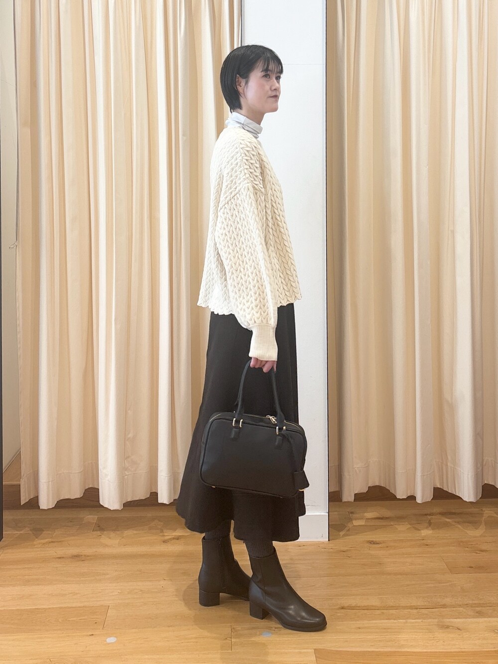 ブラック系のブーツ、ブラウン系のスカート、ブラック系のボストンバッグを着用したレディースの冬コーディネートの6枚目の写真