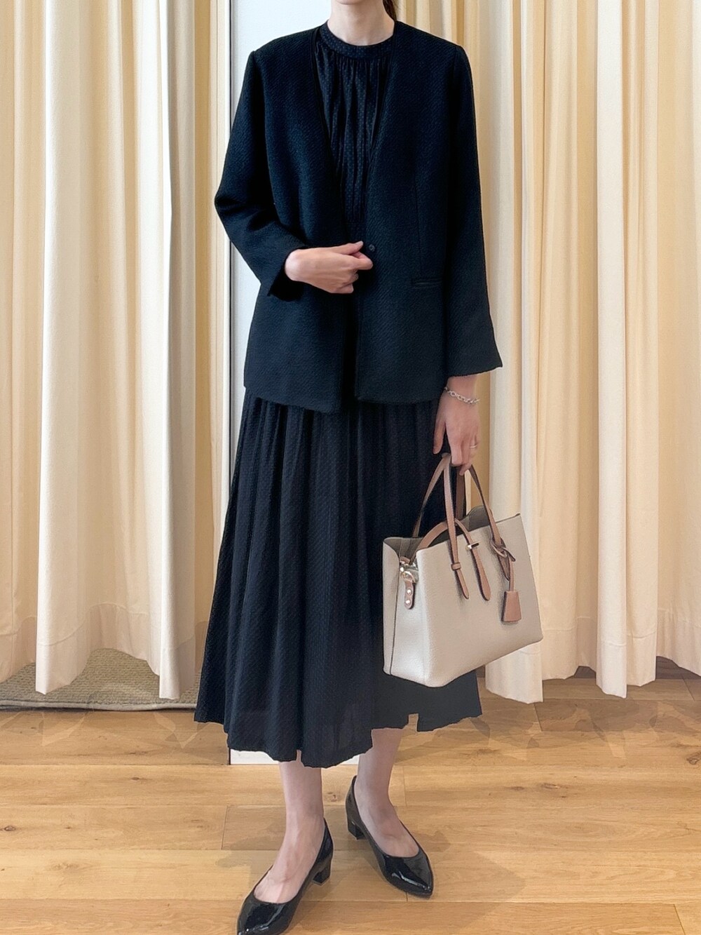 ブルー系のワンピース、ブラック系のパンプス、ベージュ系のトートバッグを着用したレディースの秋コーディネートの7枚目の写真