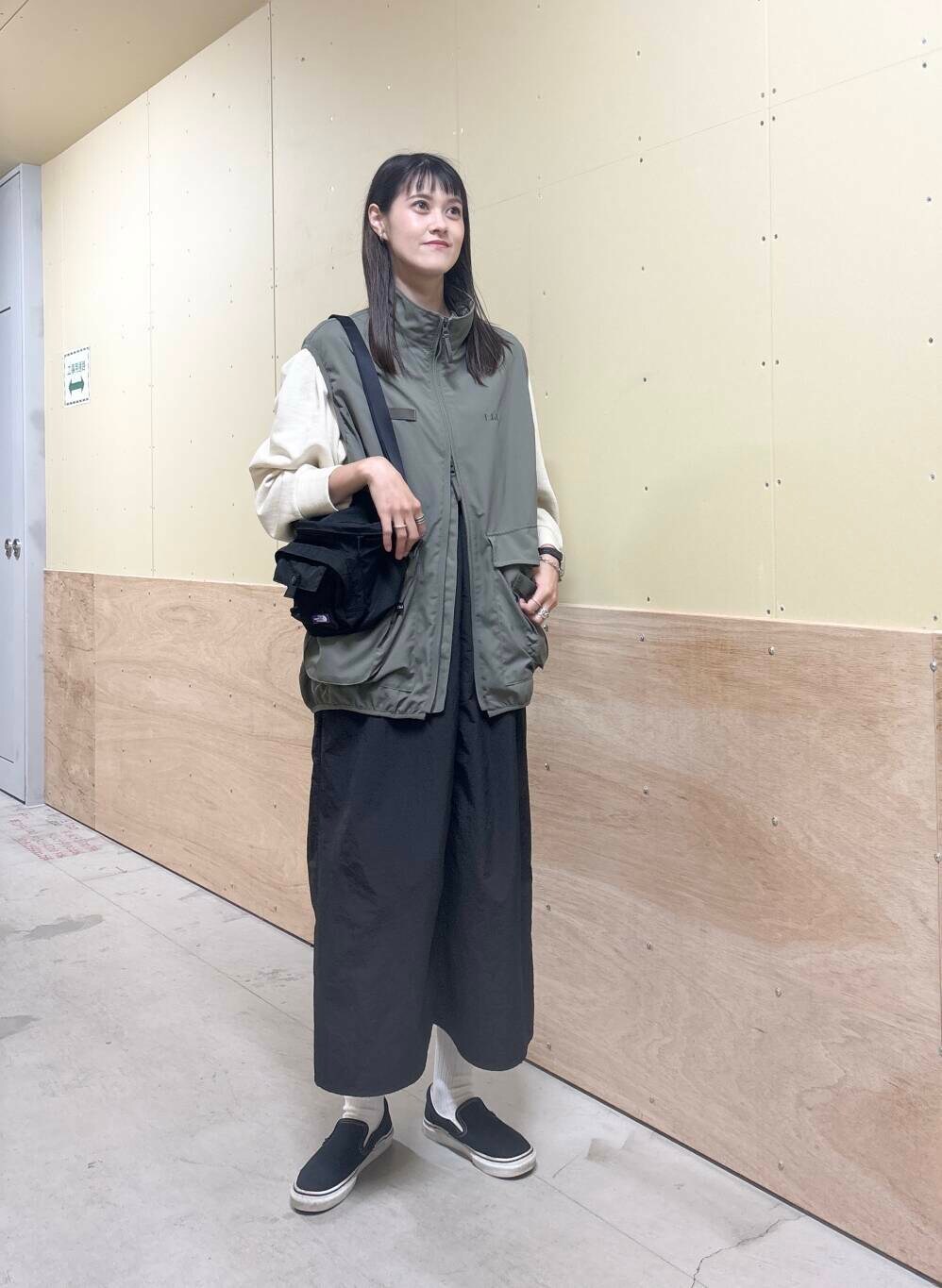 グリーン系のベスト、ブラック系のワンピース、ベージュ系のTシャツ/カットソーを着用したレディースの秋コーディネートの2枚目の写真