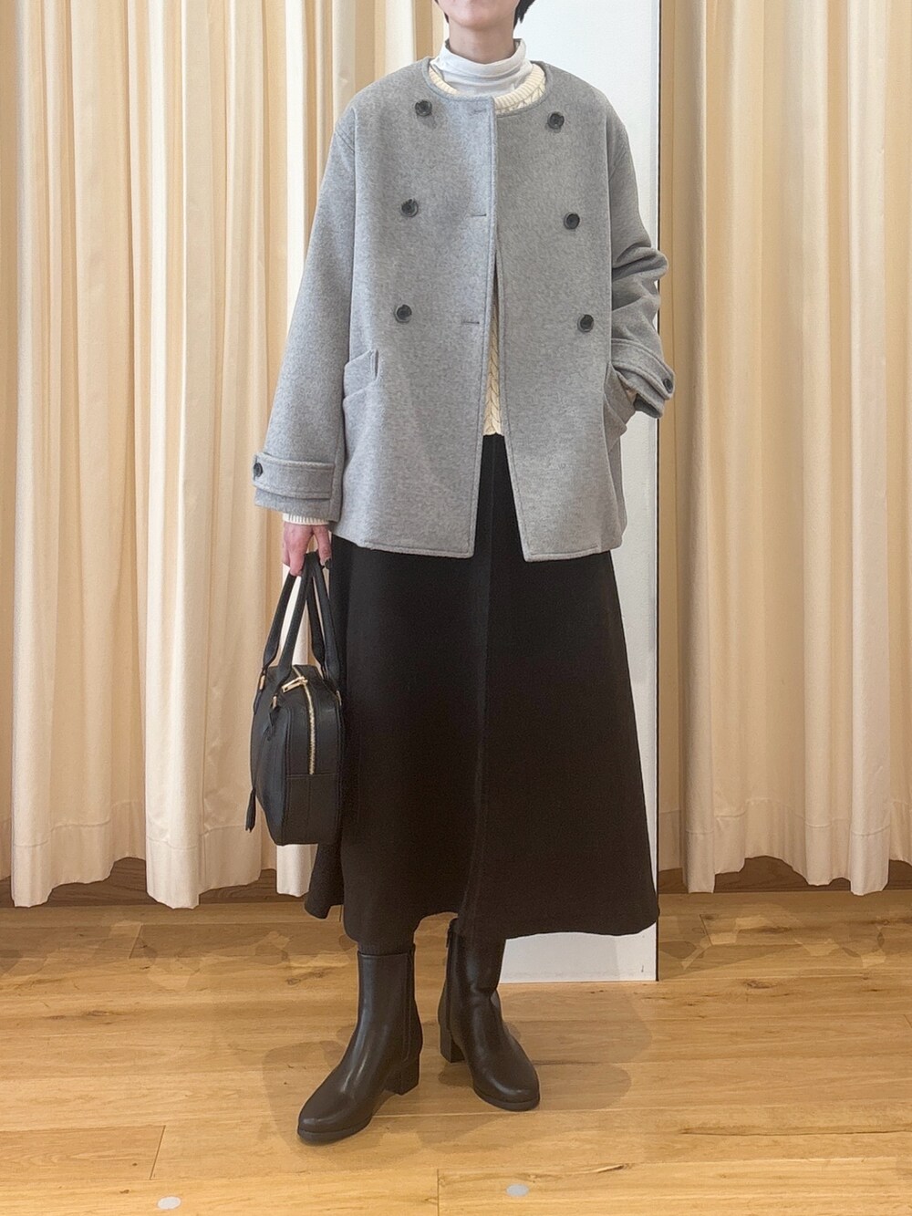 ブラック系のブーツ、ブラウン系のスカート、ブラック系のボストンバッグを着用したレディースの冬コーディネートの4枚目の写真