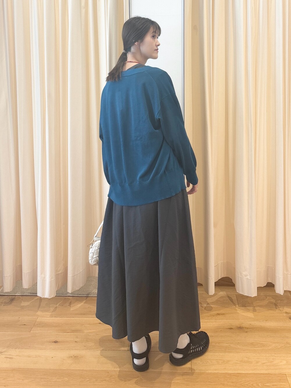 ホワイト系のショルダーバッグ、ブルー系のカーディガン/ボレロ、グレー系のワンピースを着用したレディースの夏コーディネートの7枚目の写真