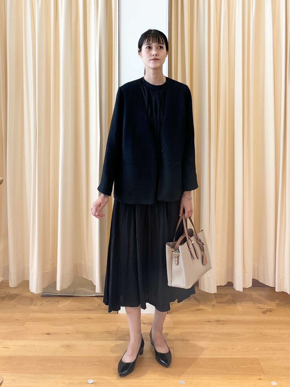 ブルー系のワンピース、ブラック系のパンプス、ベージュ系のトートバッグを着用したレディースの秋コーディネートの4枚目の写真